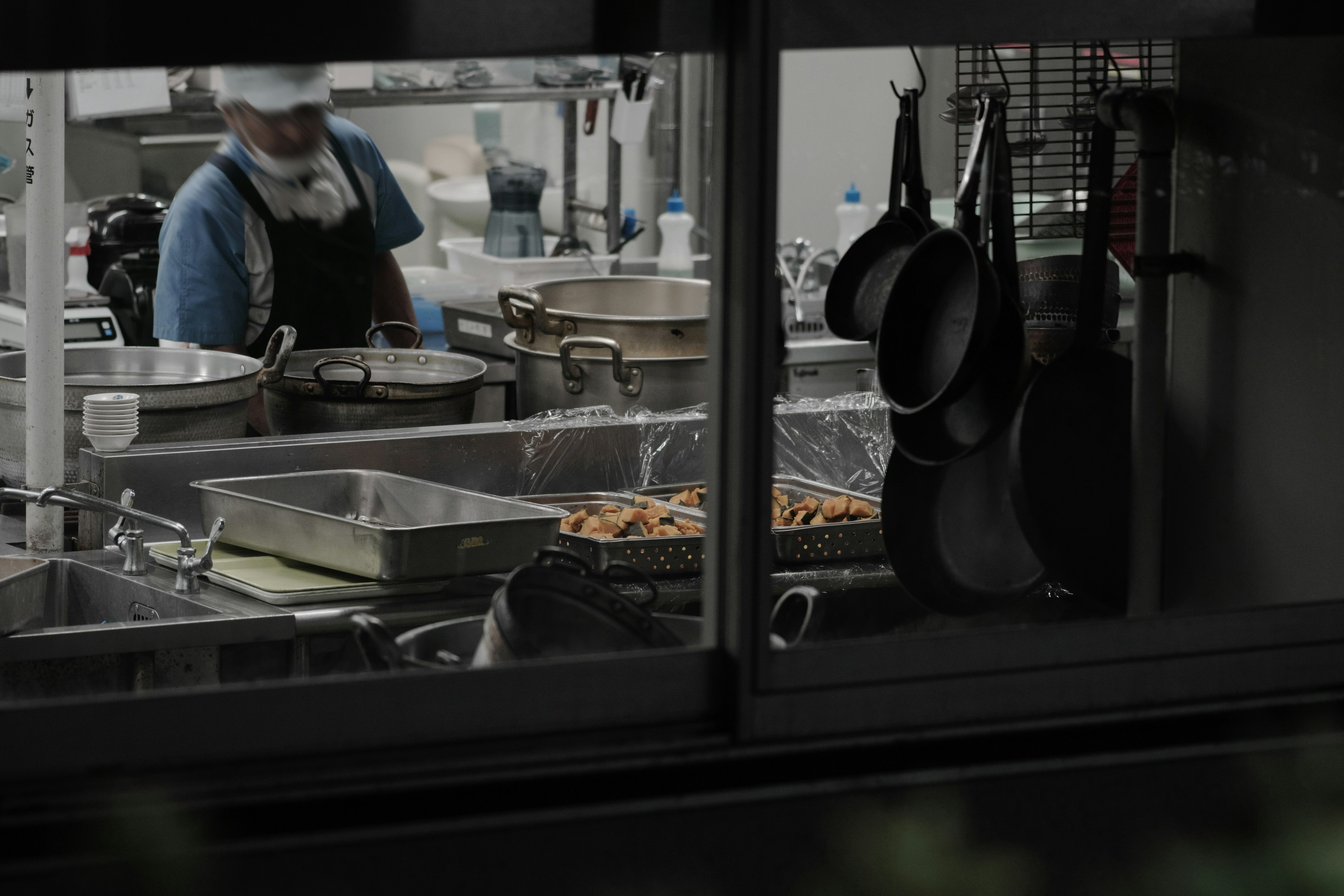 Chef preparing food in a commercial kitchen with pots and pans