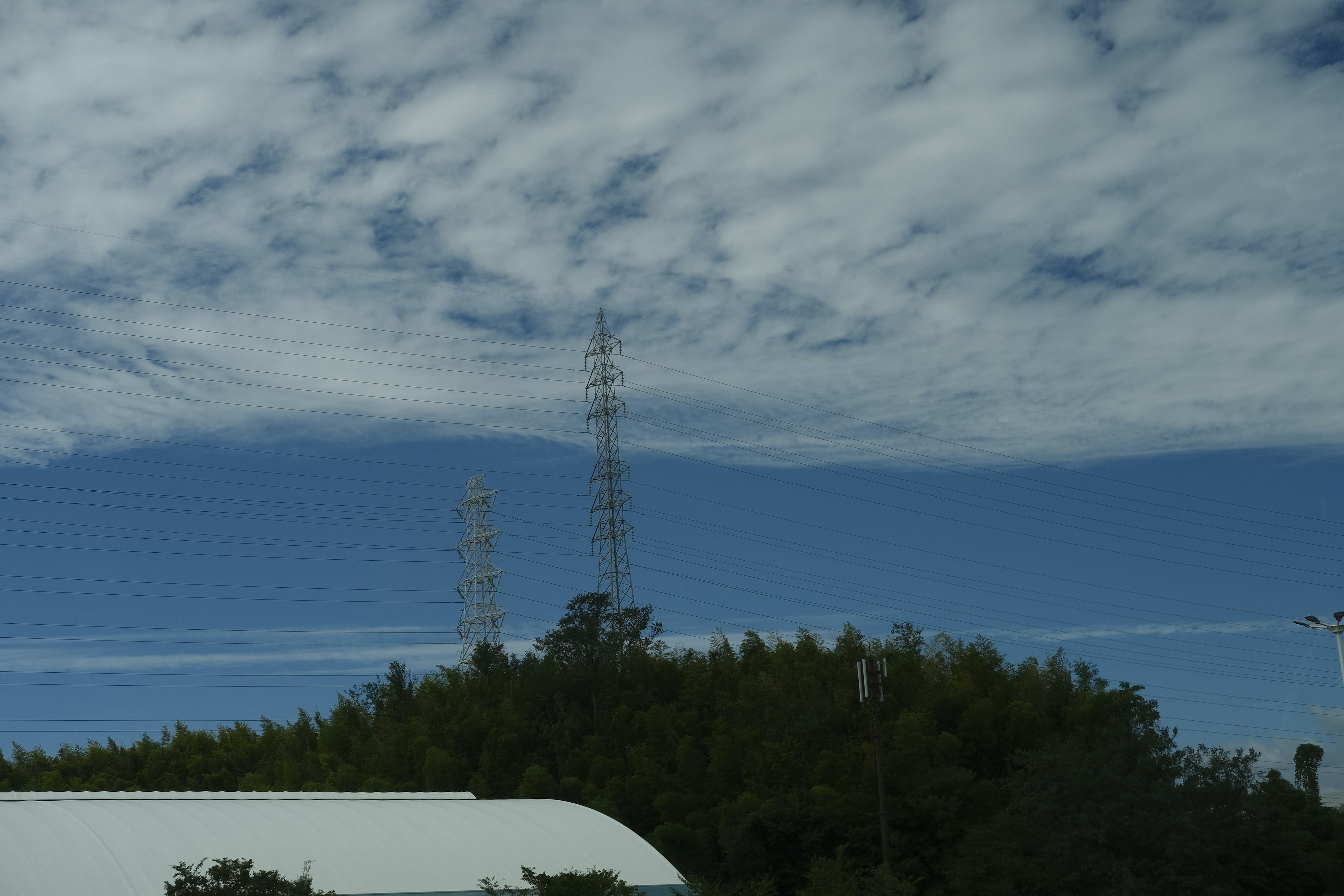 Paisaje con torres de comunicación bajo un cielo azul con nubes