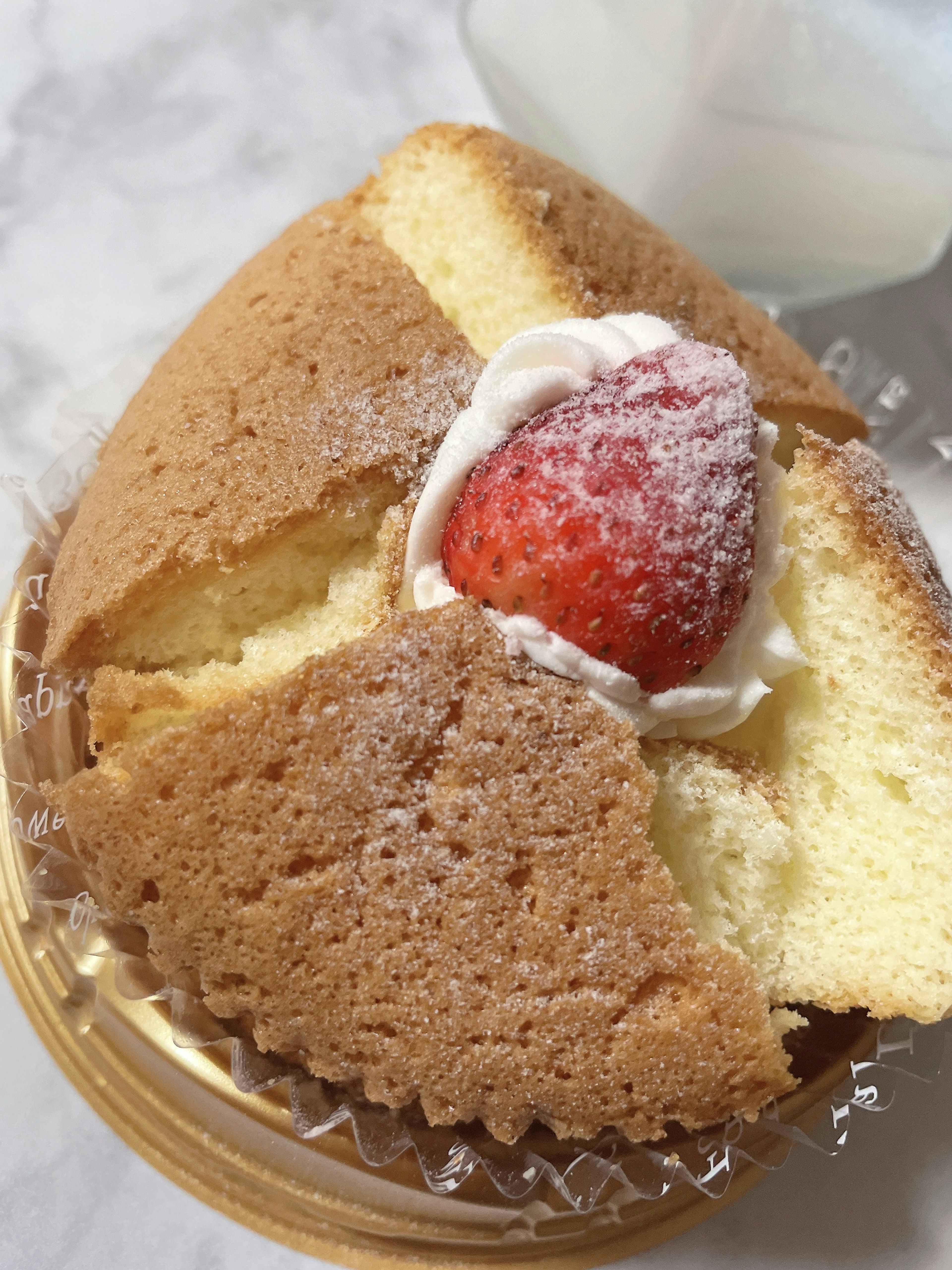 Cross-section of a freshly baked cake topped with cream and a strawberry