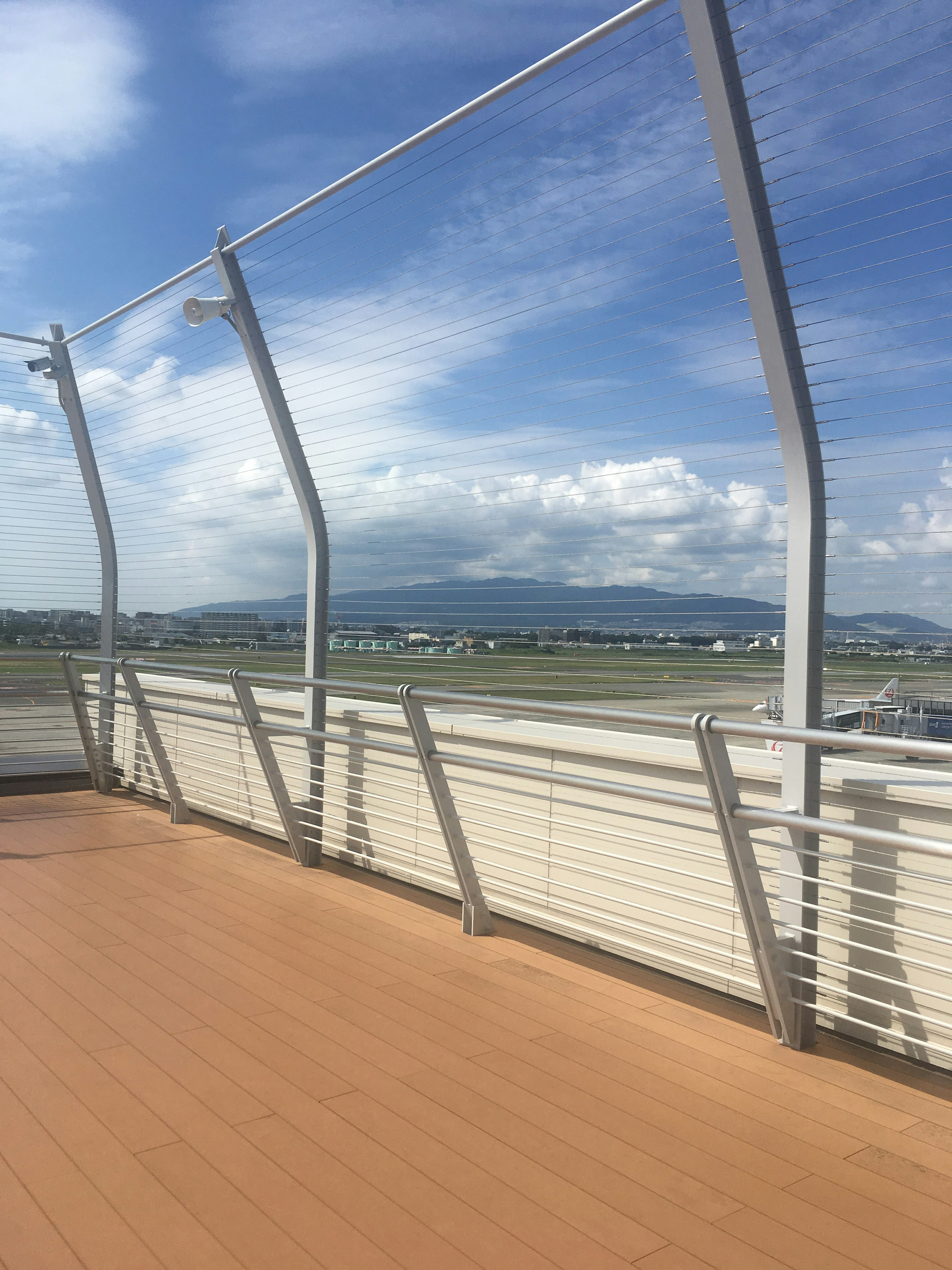 Vista de una terraza de observación del aeropuerto con cielo azul y nubes