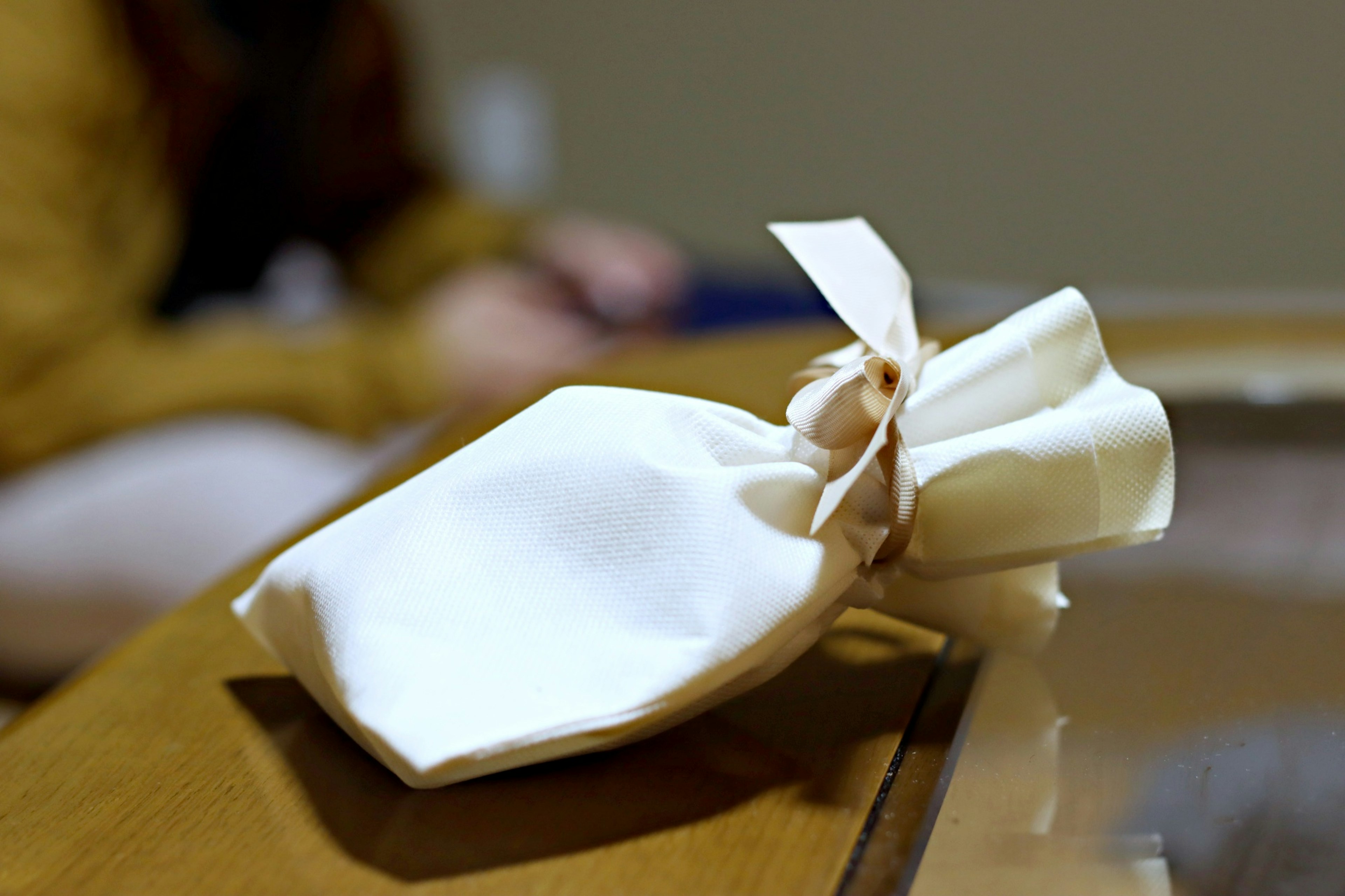 Un petit objet enveloppé dans un tissu blanc est posé sur une table