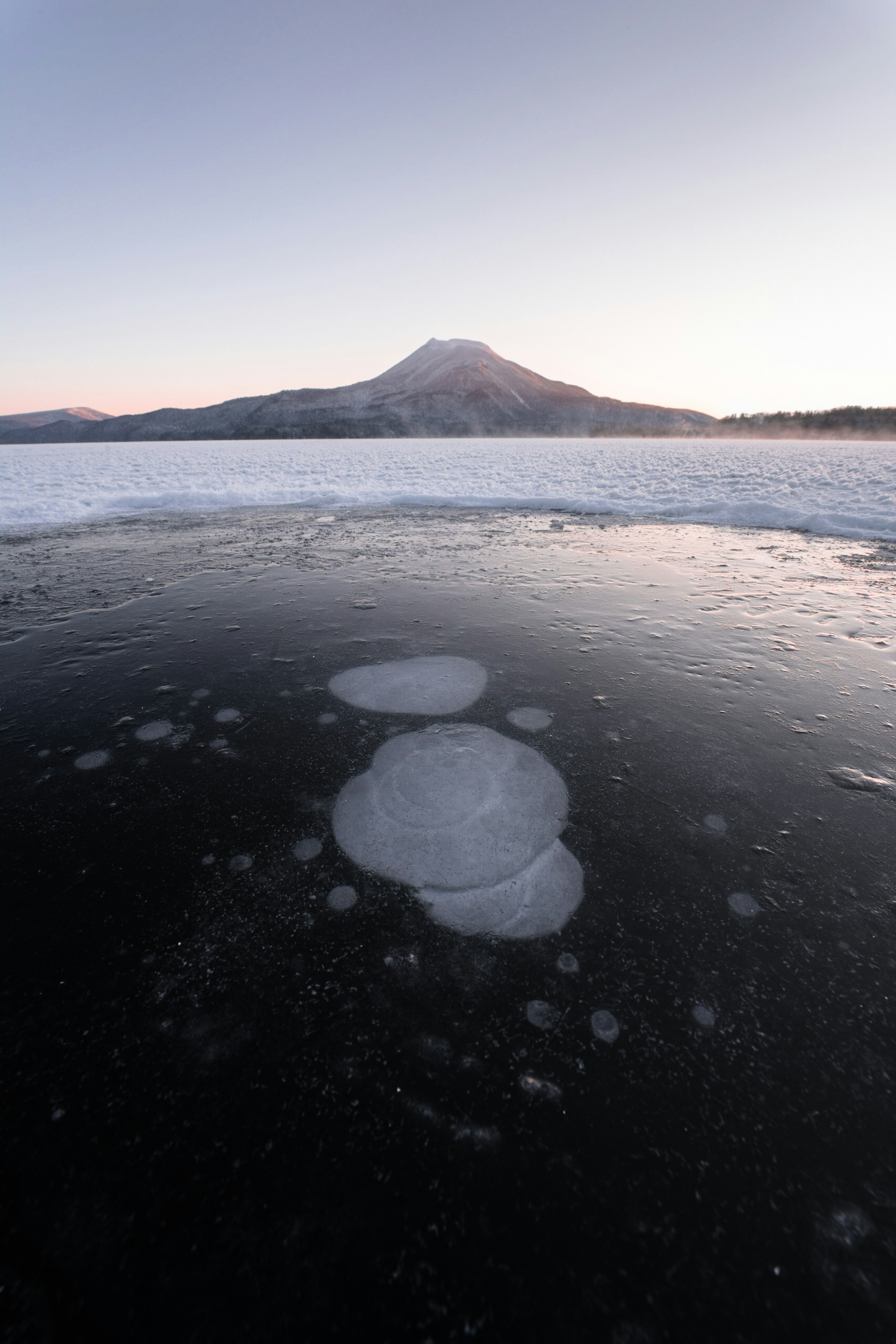 凍った湖の上に浮かぶ氷の塊と遠くの山の風景