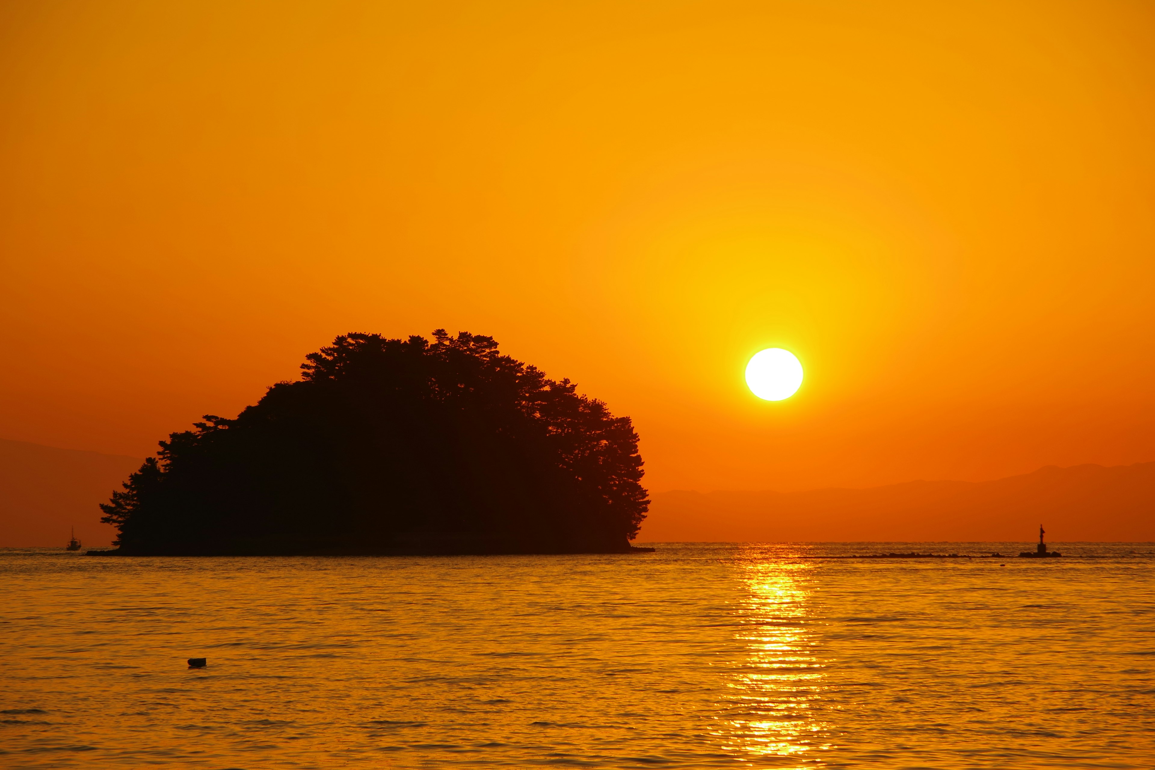 Pemandangan matahari terbenam yang indah di atas lautan dengan siluet pulau kecil