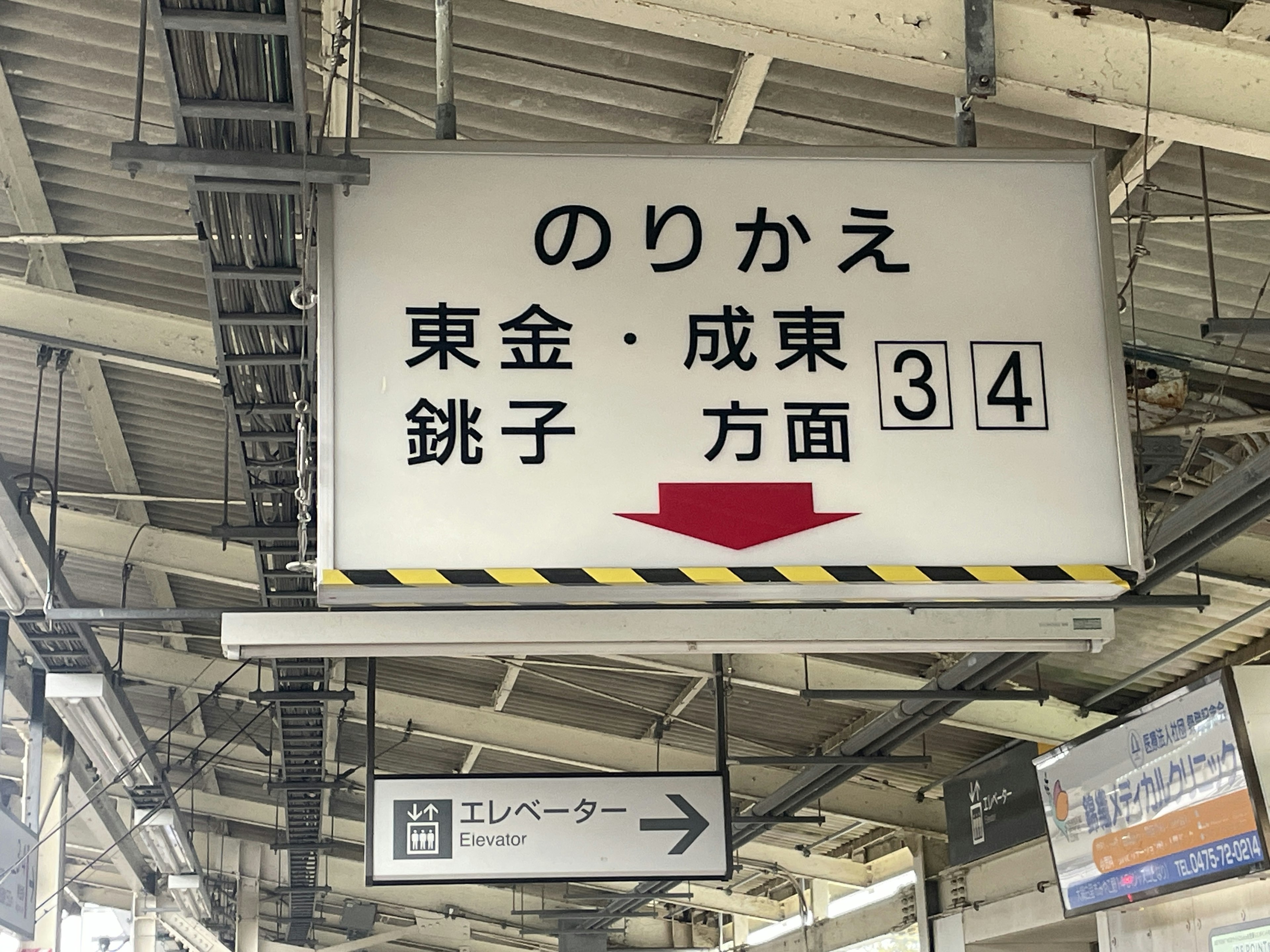 Señal de estación indicando transferencia a Togane y Narita en la plataforma 34