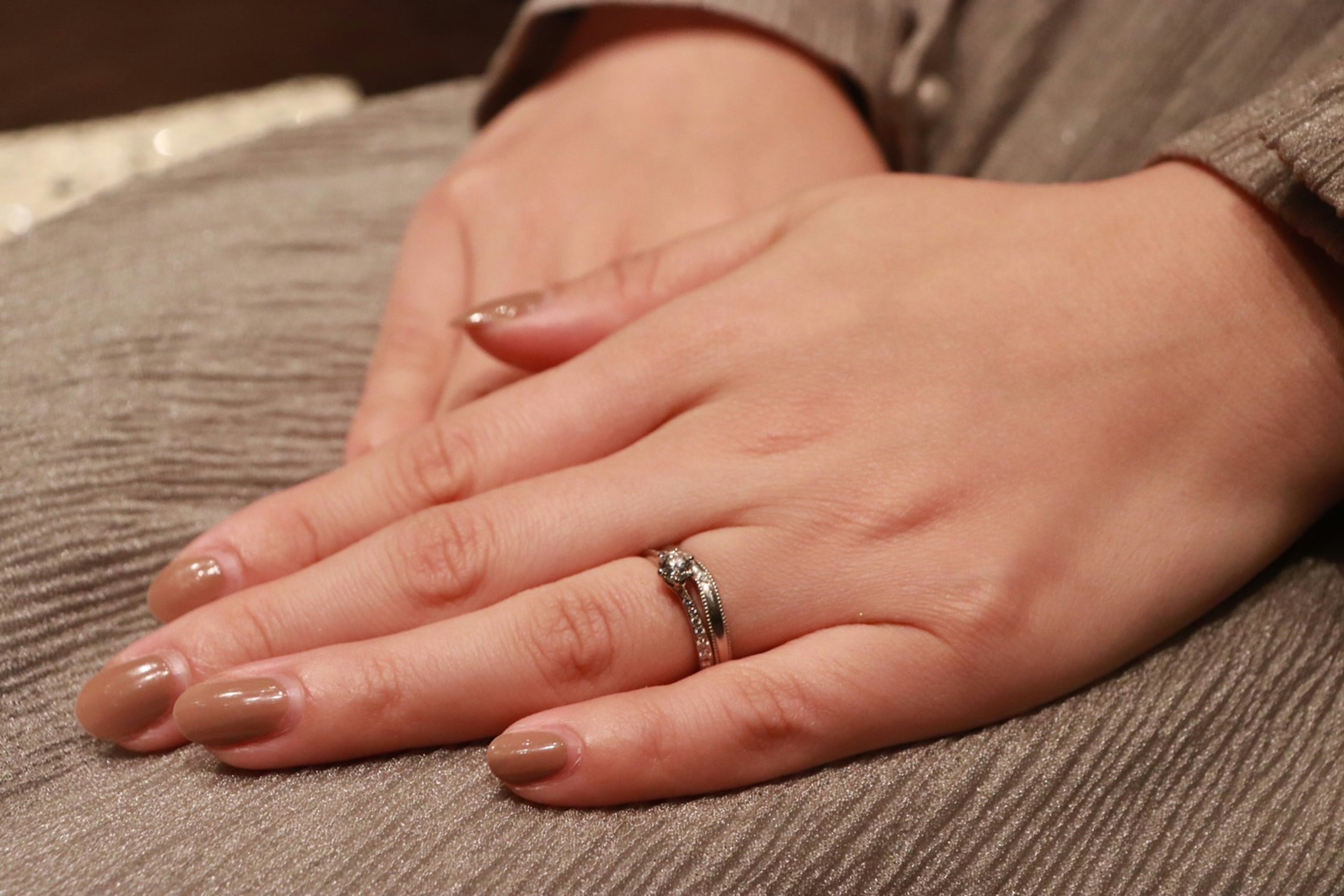 Gros plan sur des mains avec une bague en argent et un vernis à ongles neutre