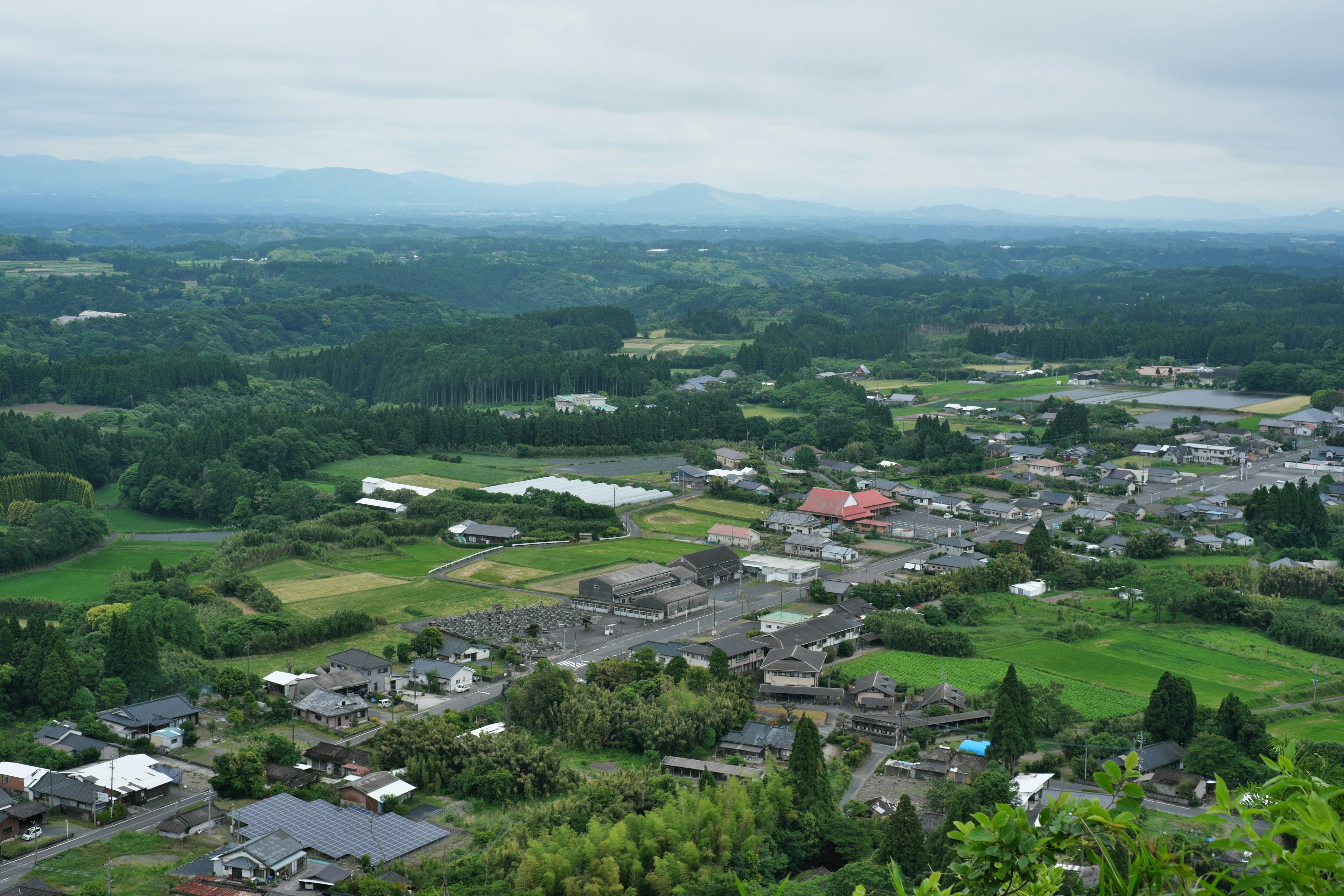 A scenic view from a mountain top overlooking a lush countryside and village