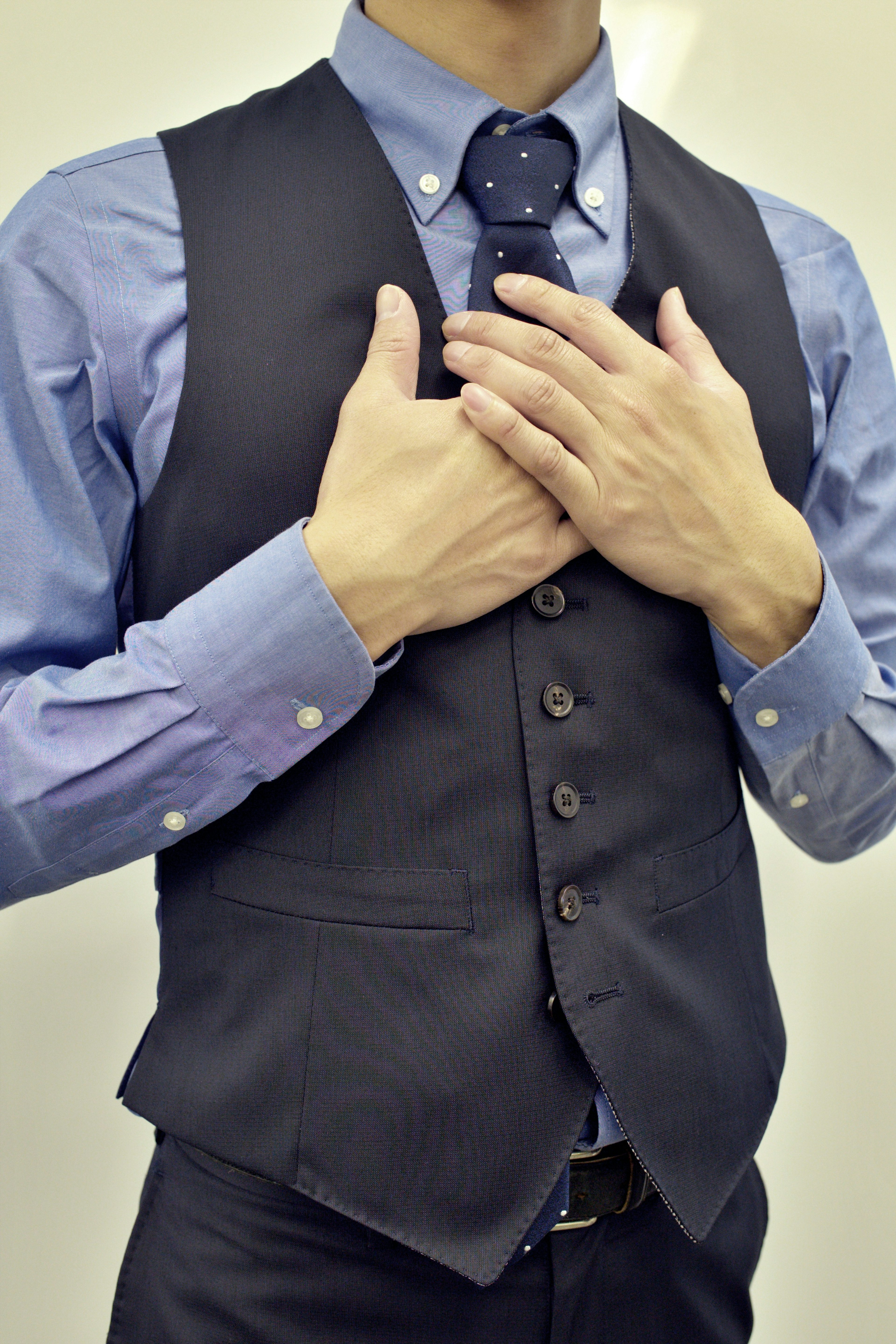 Un homme portant un gilet de costume avec les mains sur la poitrine