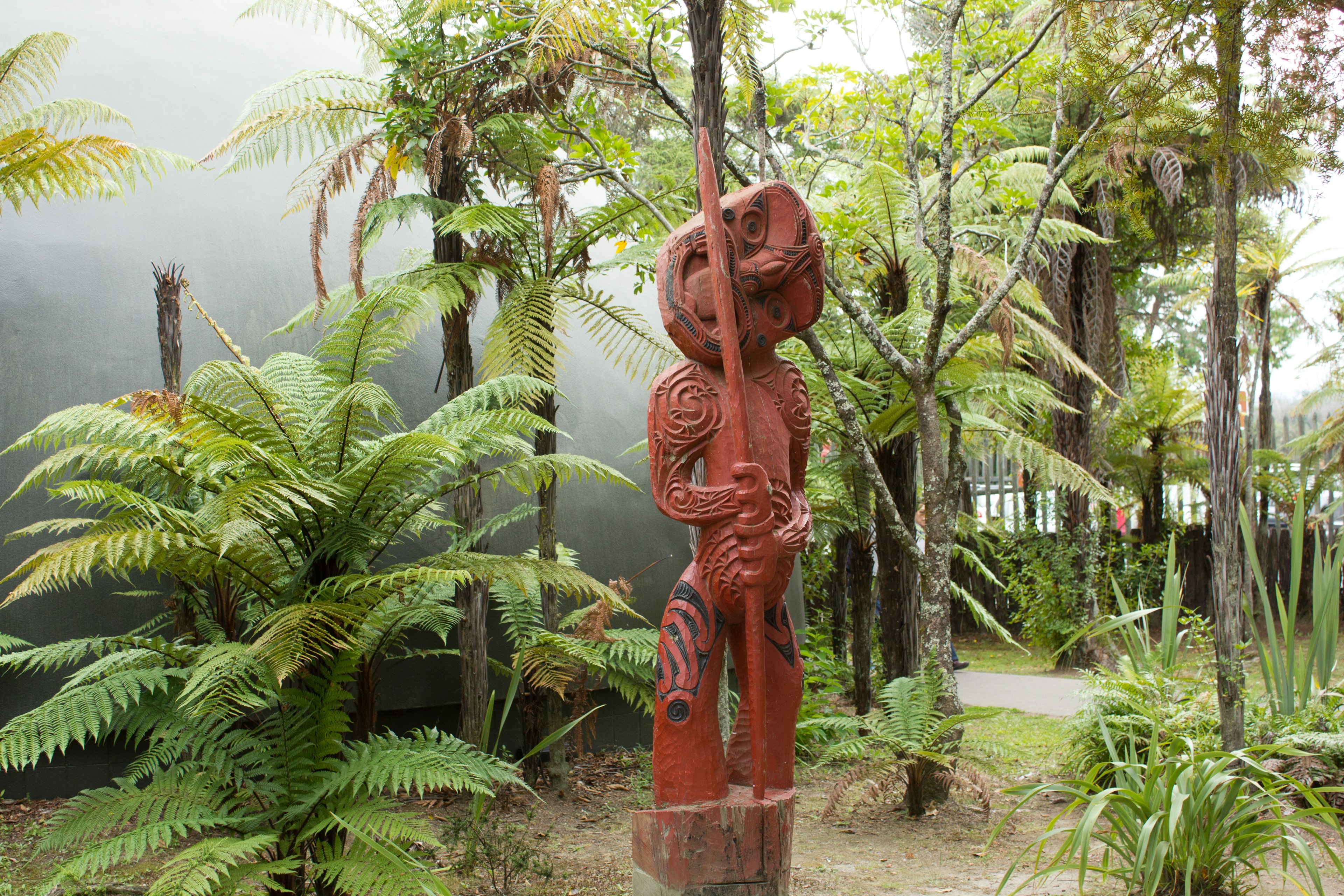 Una escultura de madera roja rodeada de plantas verdes exuberantes en un jardín