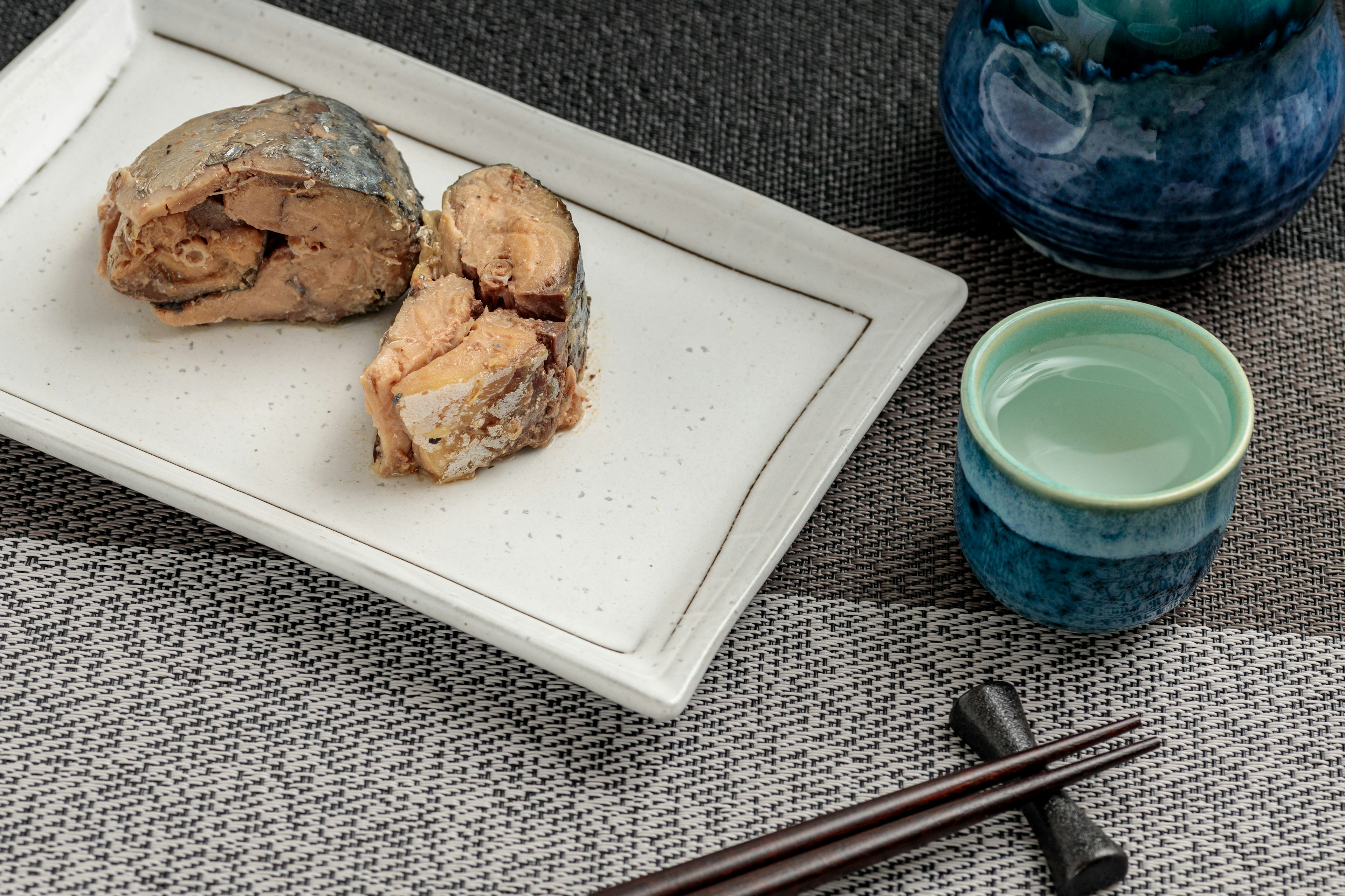 Poisson grillé servi sur une assiette avec une tasse en céramique bleue