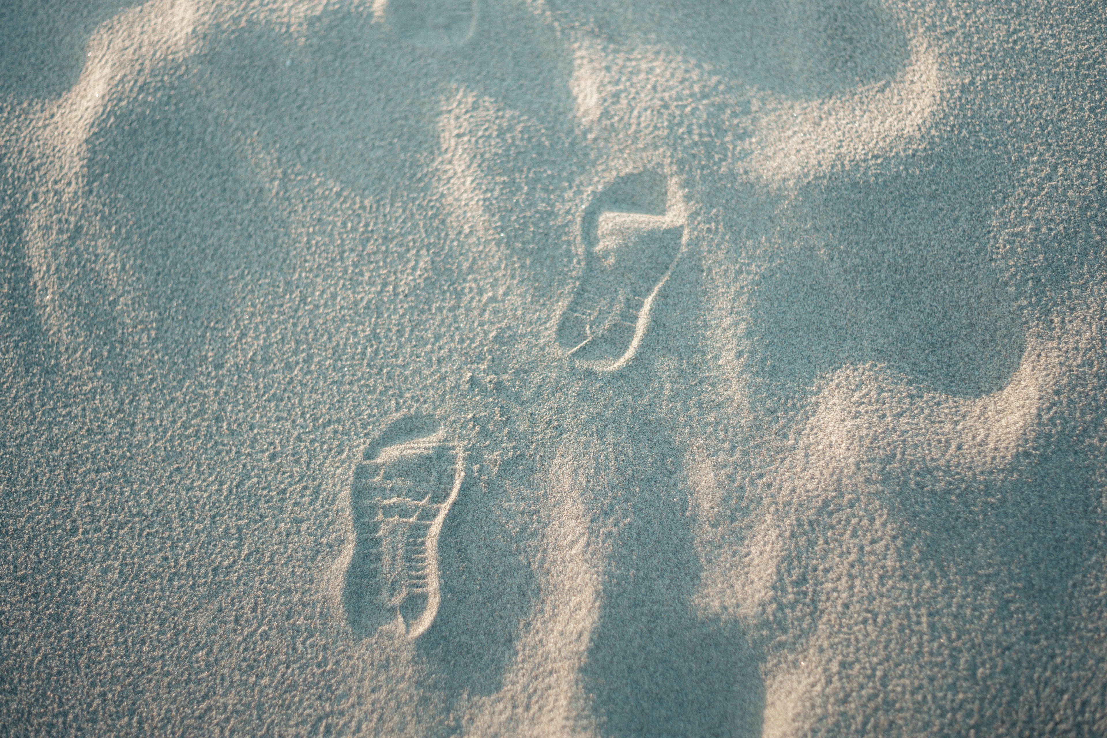 Footprints on sandy beach with wave patterns