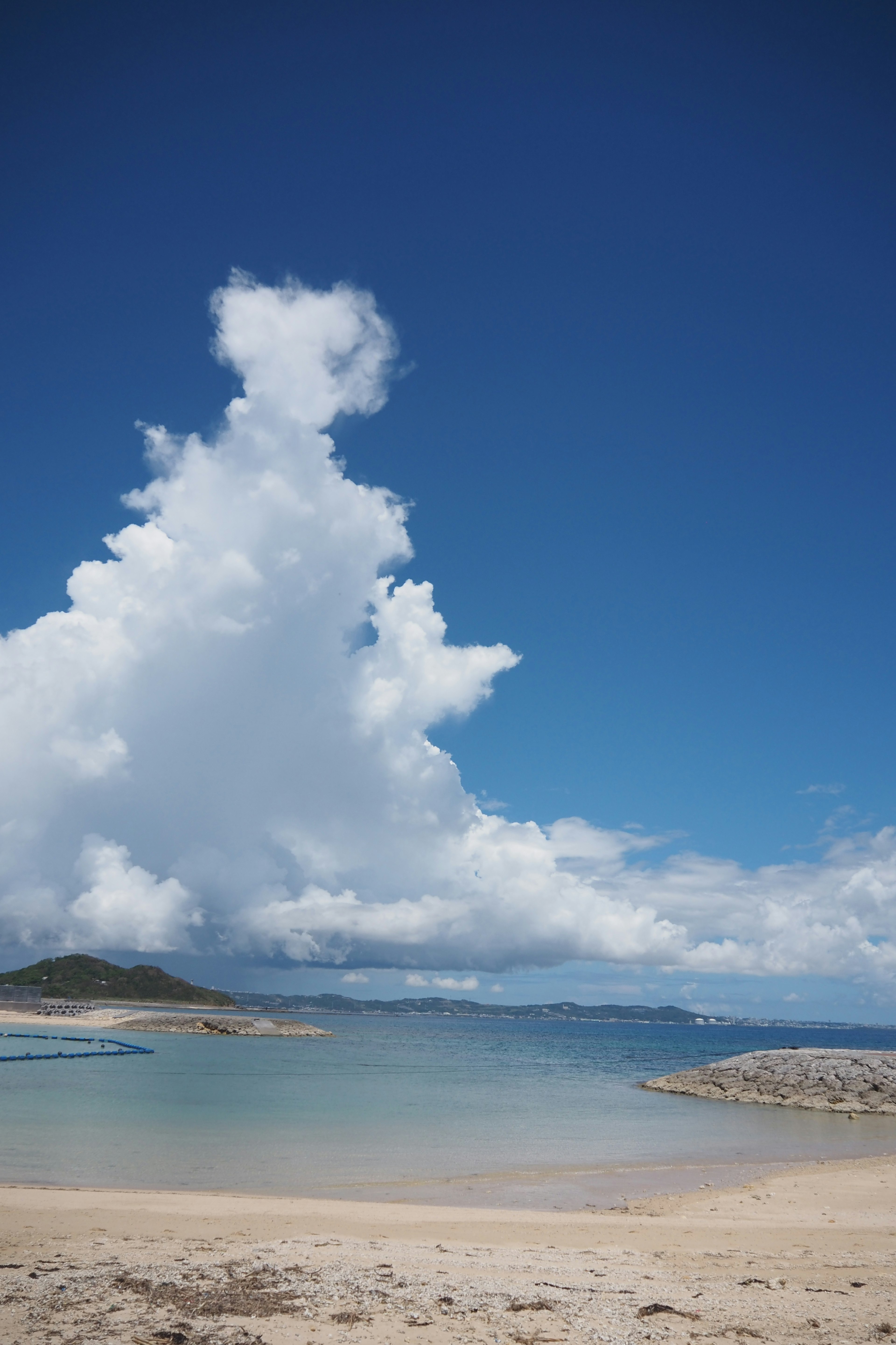 Pemandangan pantai dengan langit biru dan awan putih berbulu