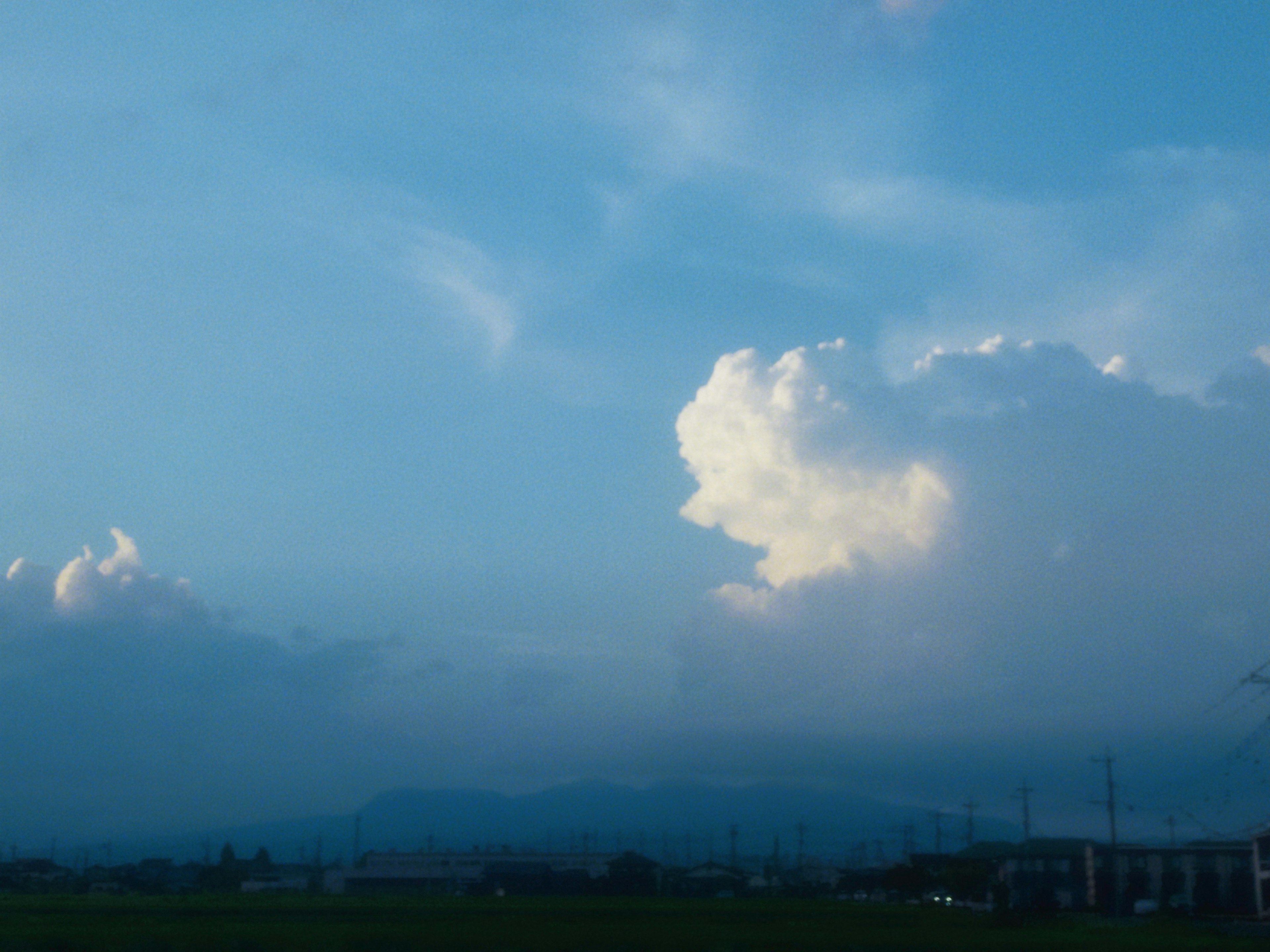 Awan putih di langit biru dengan pegunungan di kejauhan