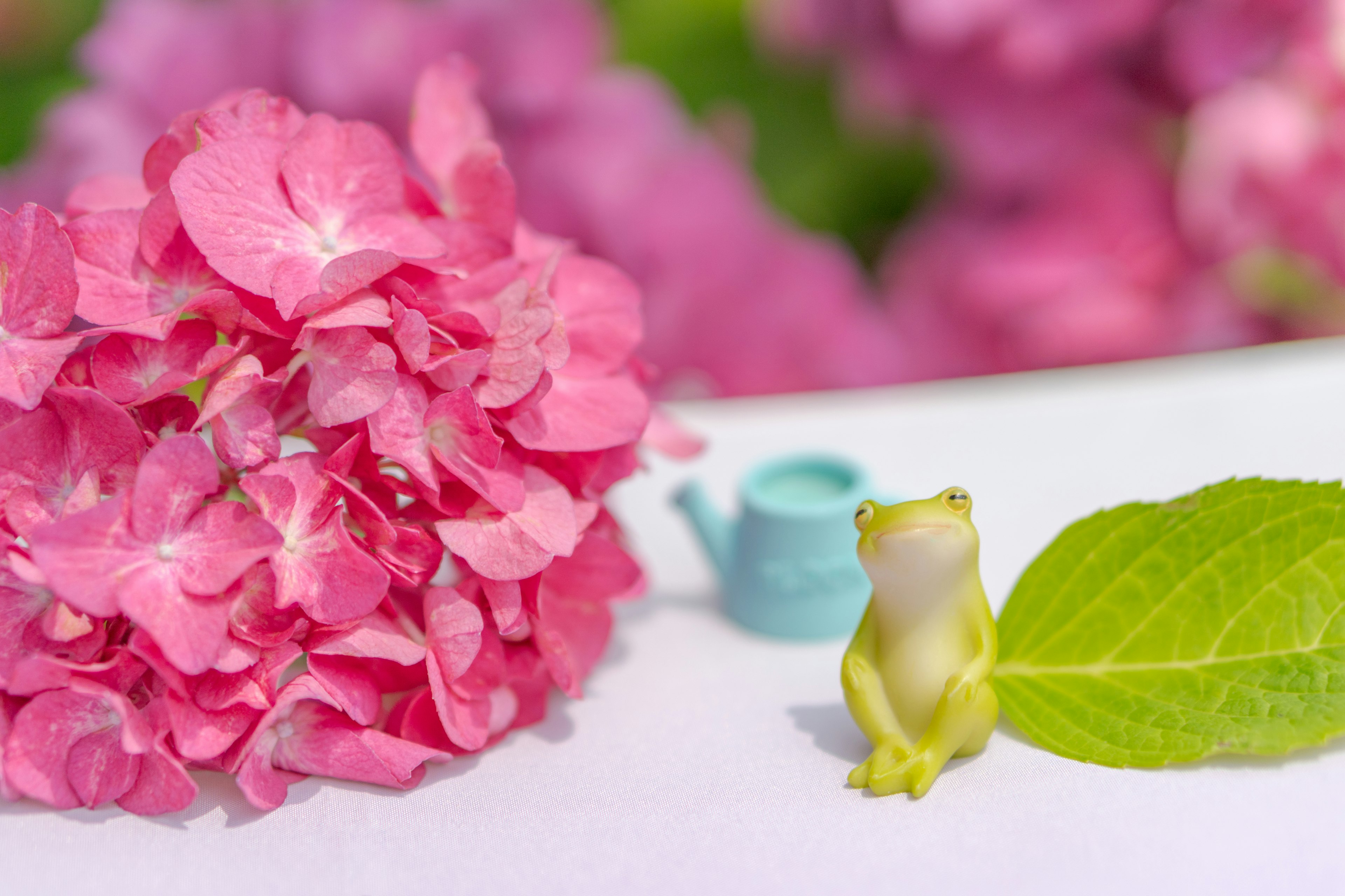 Una escena encantadora con una flor de hortensia rosa y una pequeña figura de rana