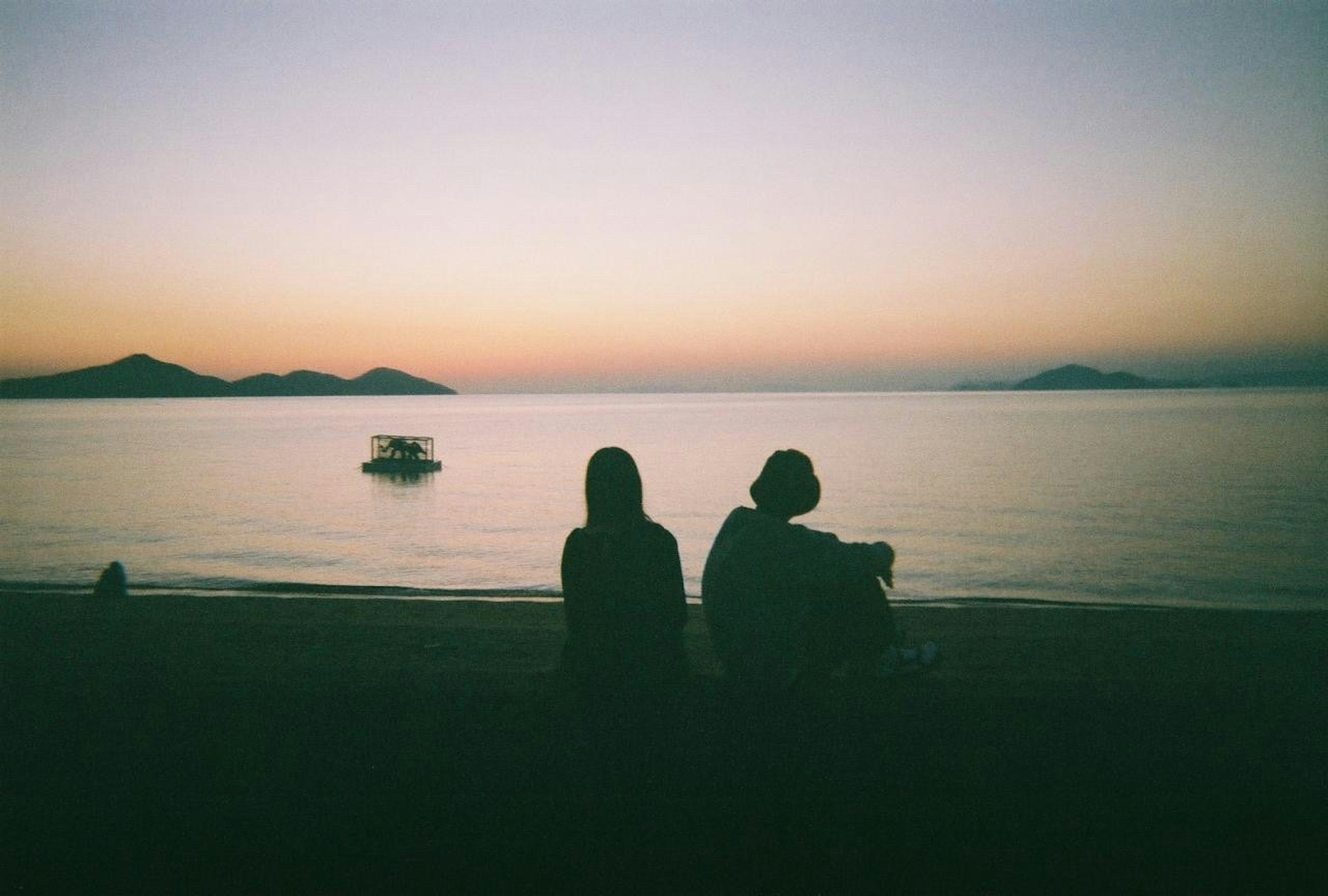 Silhouette di due persone che guardano il mare al tramonto