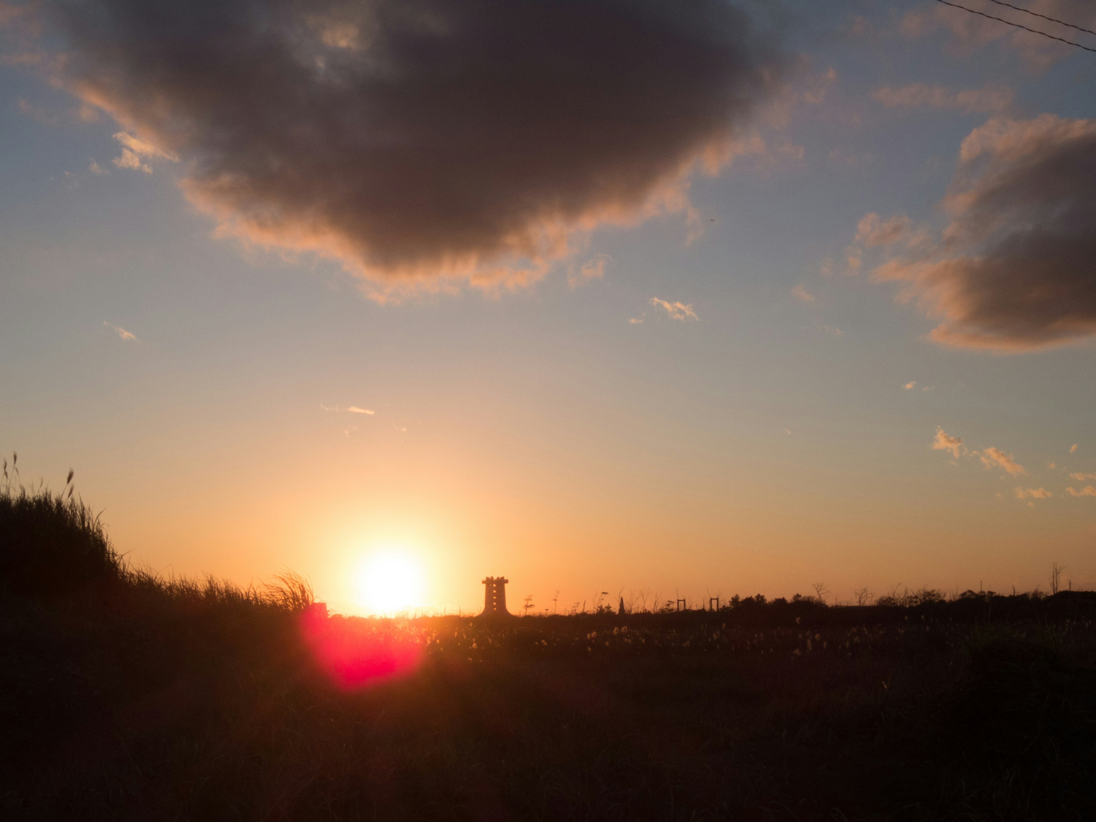 Silhouette of a tower against a sunset with clouds