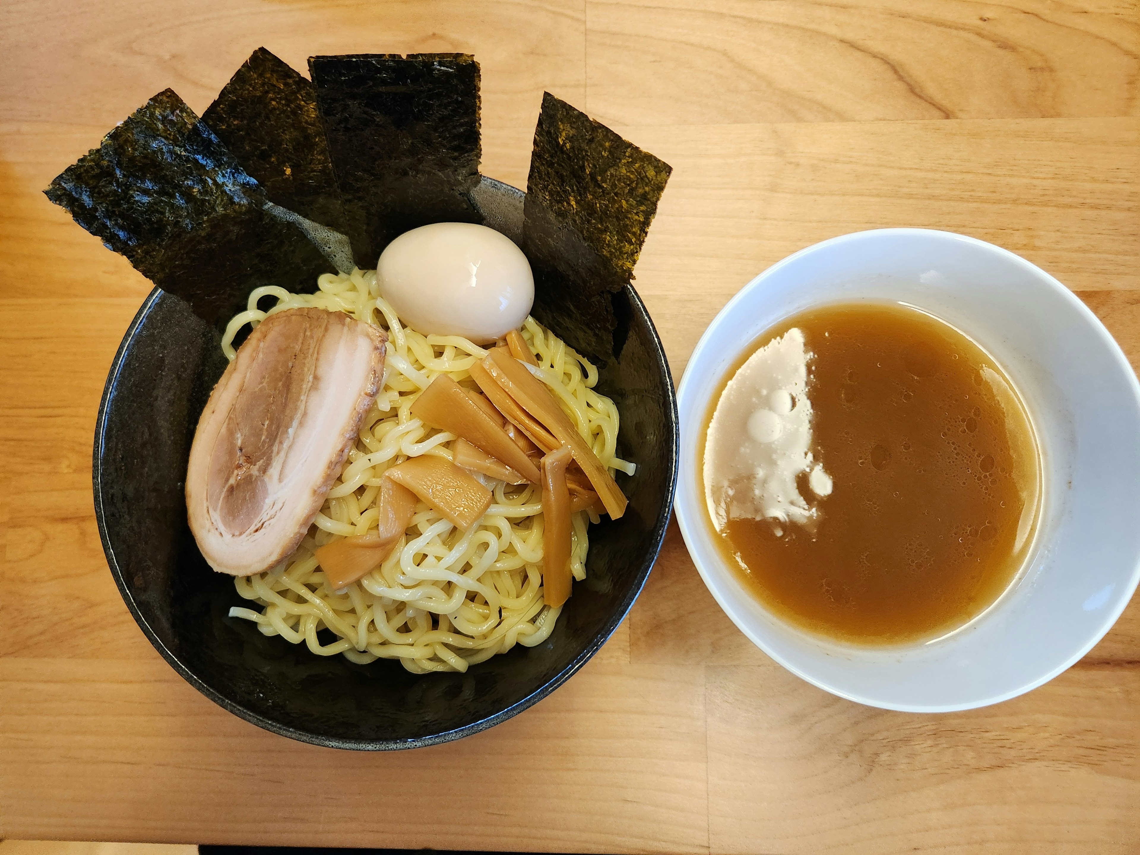 Tsukemen servito in una ciotola nera con salsa di immersione in una ciotola bianca