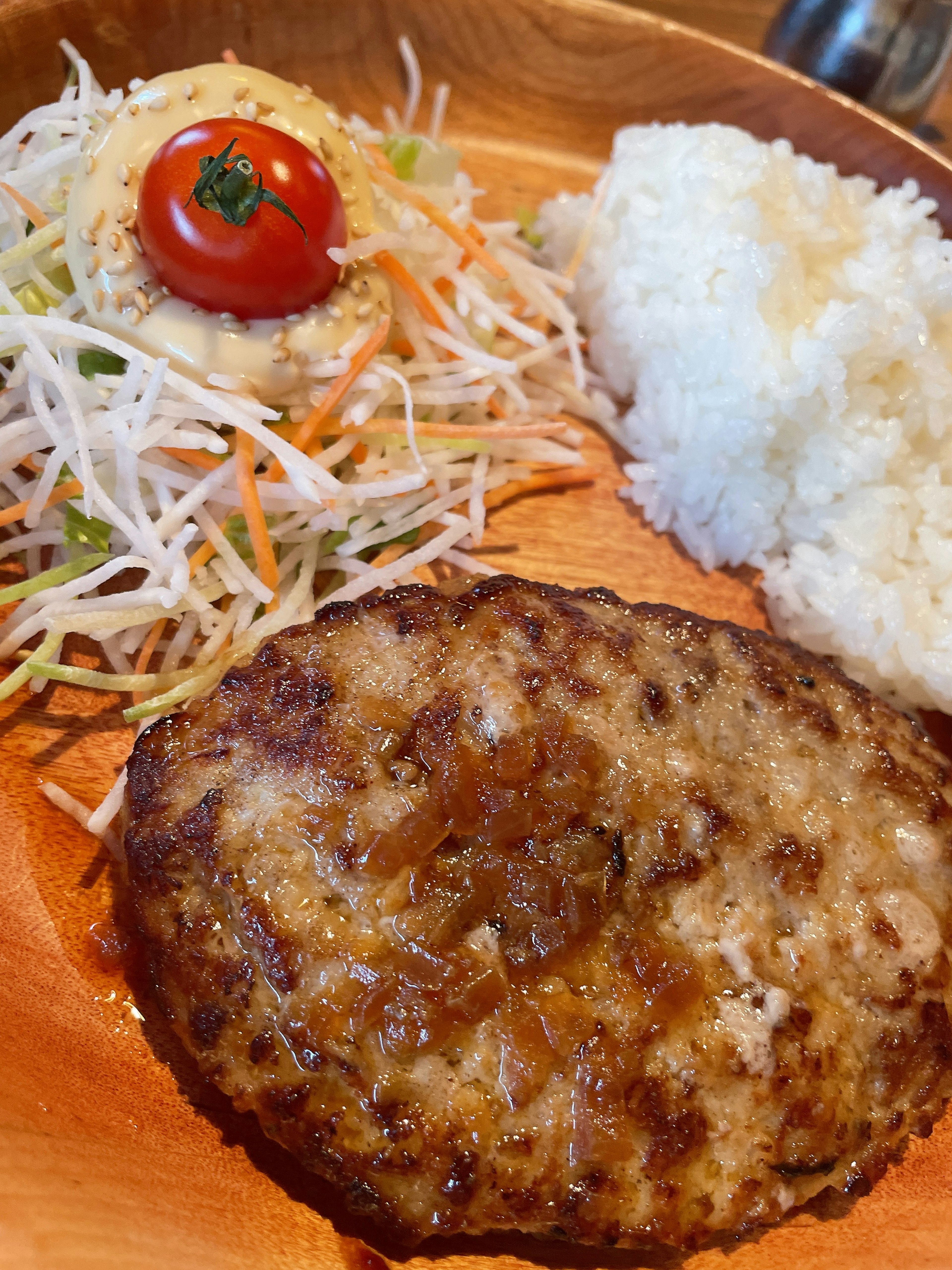 Plate featuring a hamburger steak, salad, rice, and cherry tomato