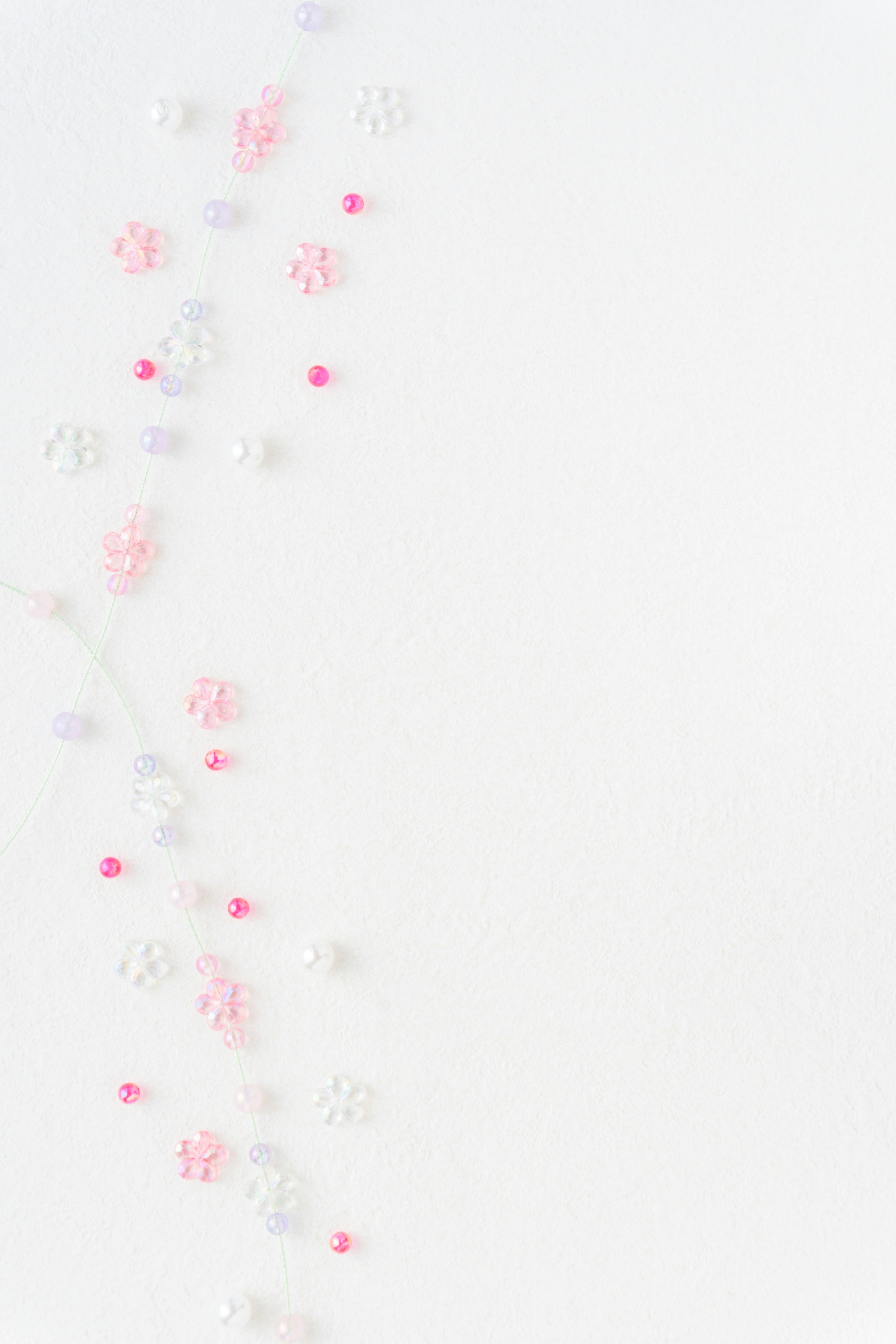 Perlas en forma de flor de colores esparcidas sobre un fondo blanco