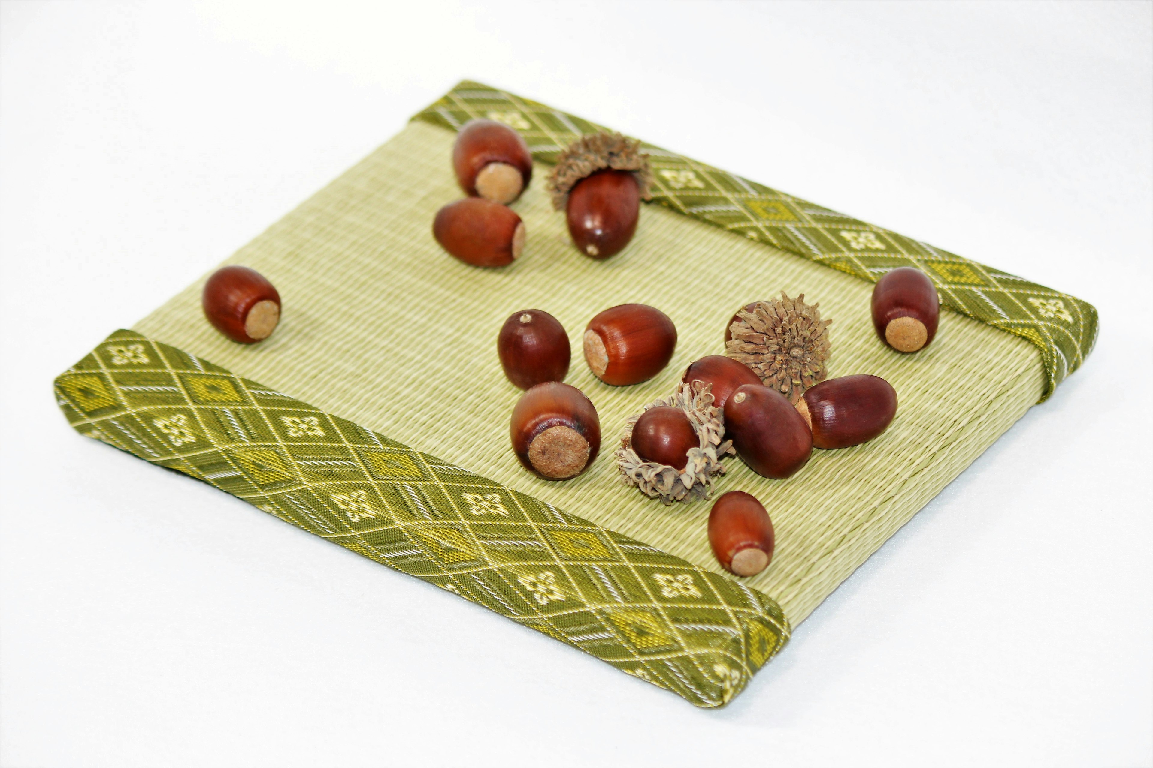 Red acorns and their caps scattered on a green decorative mat