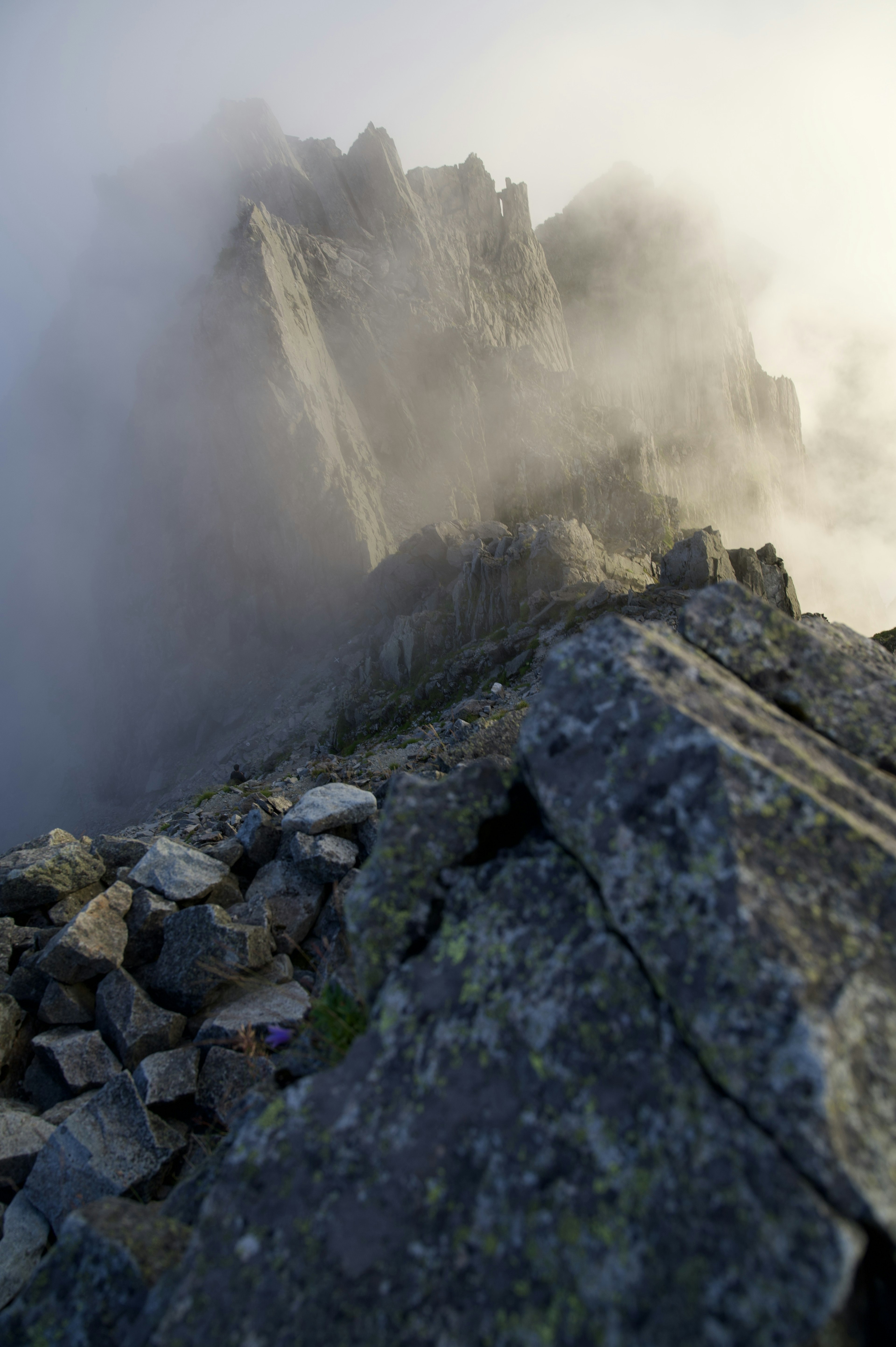 Acercamiento a un pico montañoso rocoso envuelto en niebla