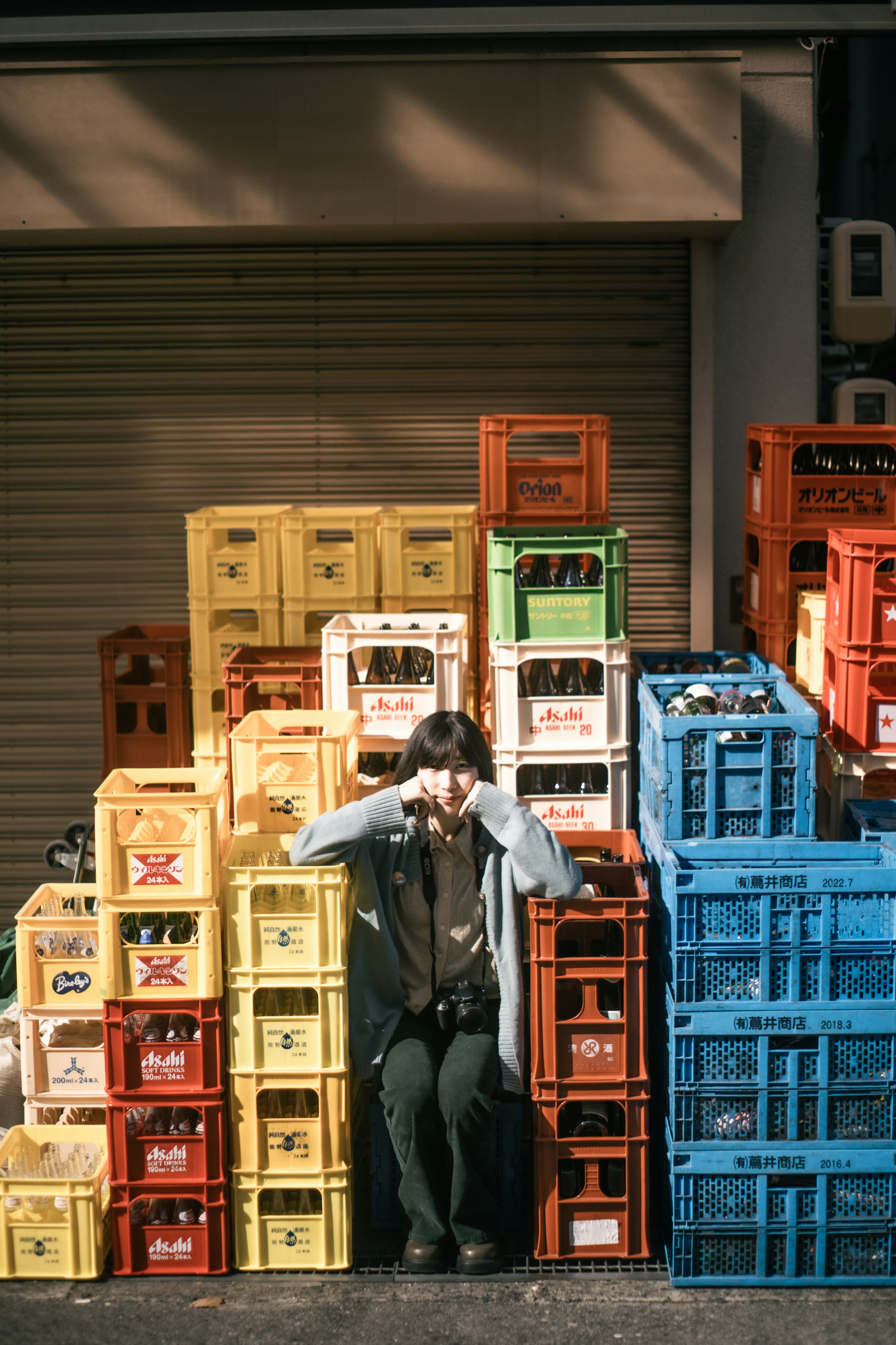 Mujer sentada frente a cajas de plástico coloridas