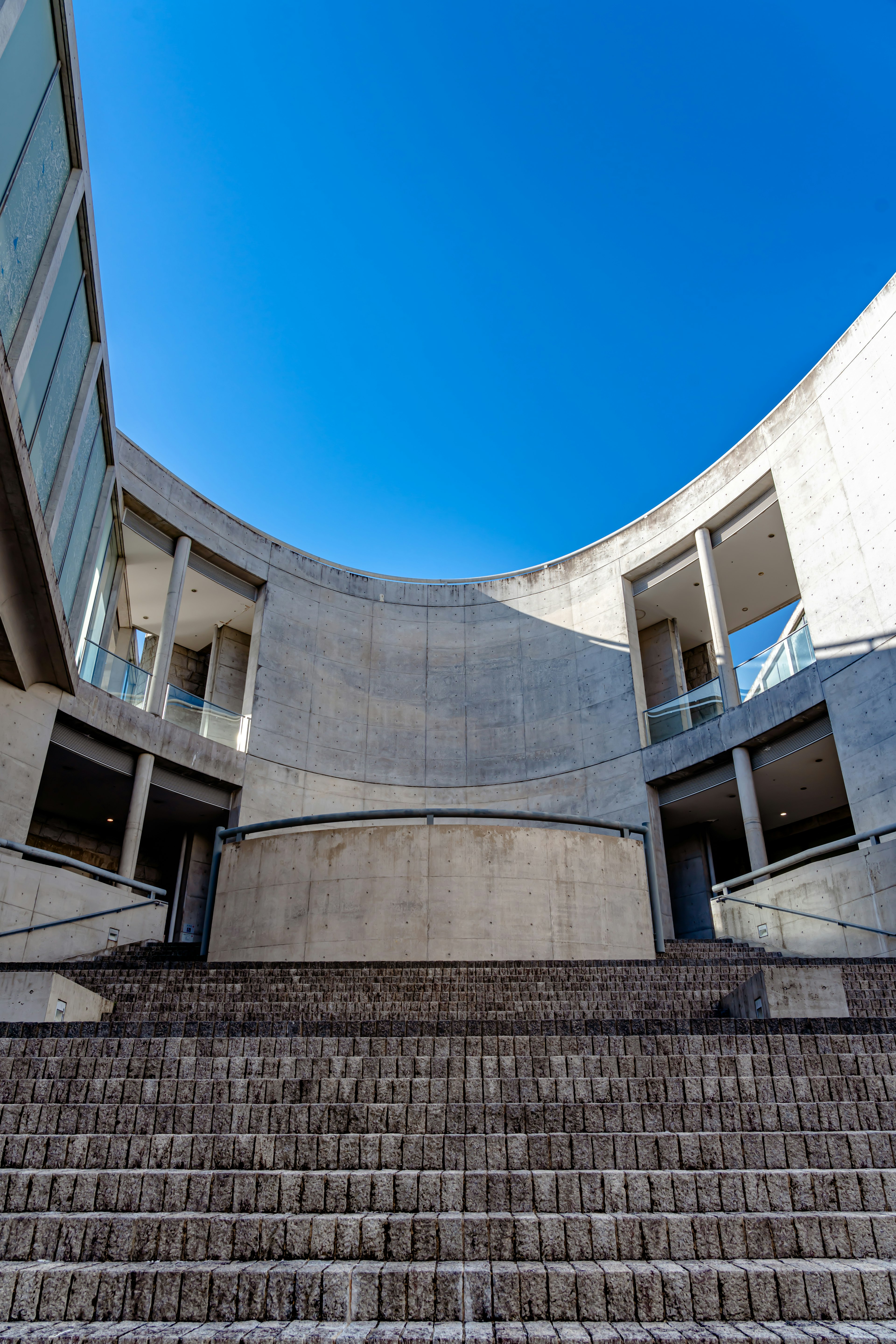 Aussicht auf ein rundes Gebäude mit Treppen unter einem blauen Himmel