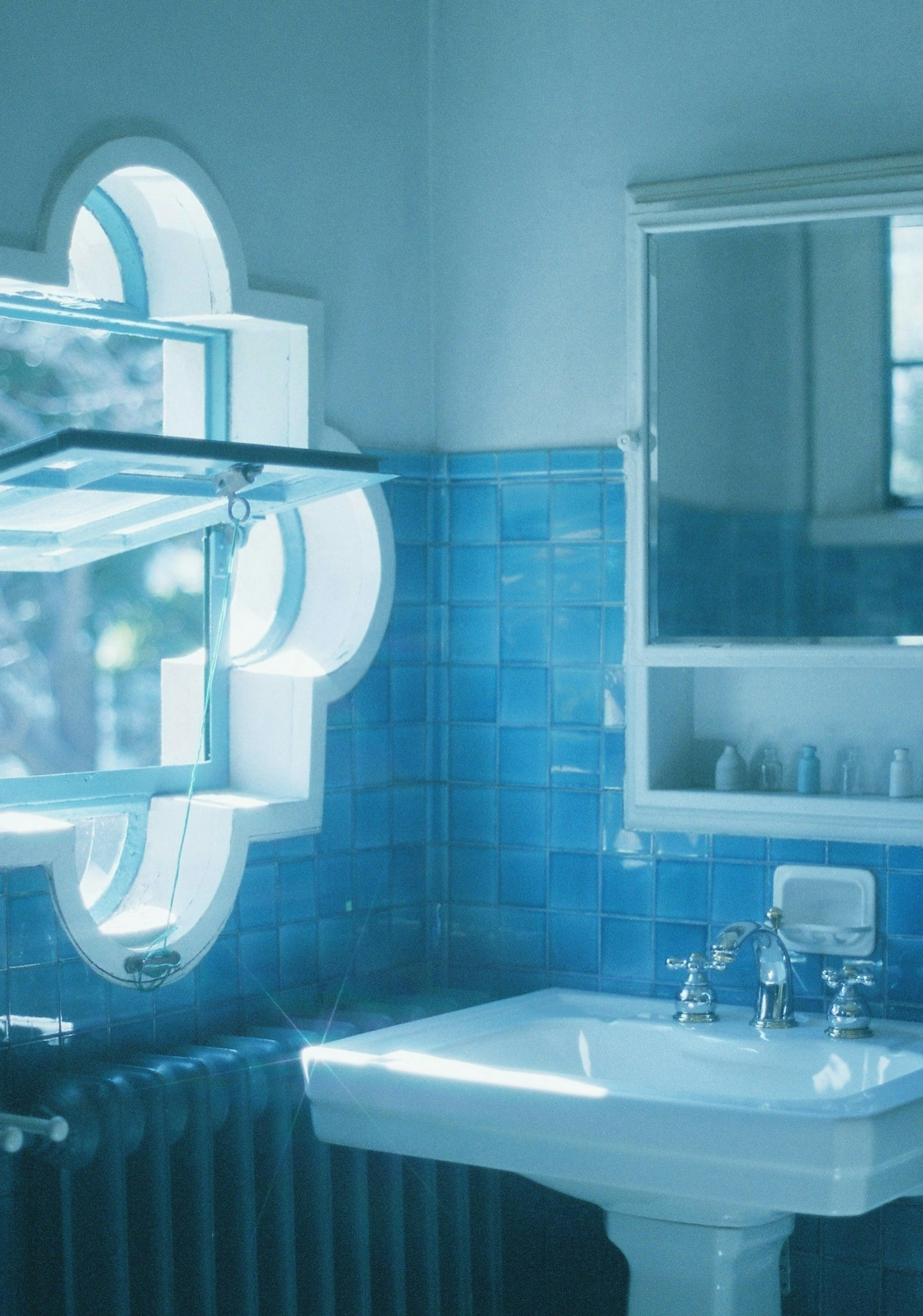 Bagno con piastrelle blu con lavabo e specchio