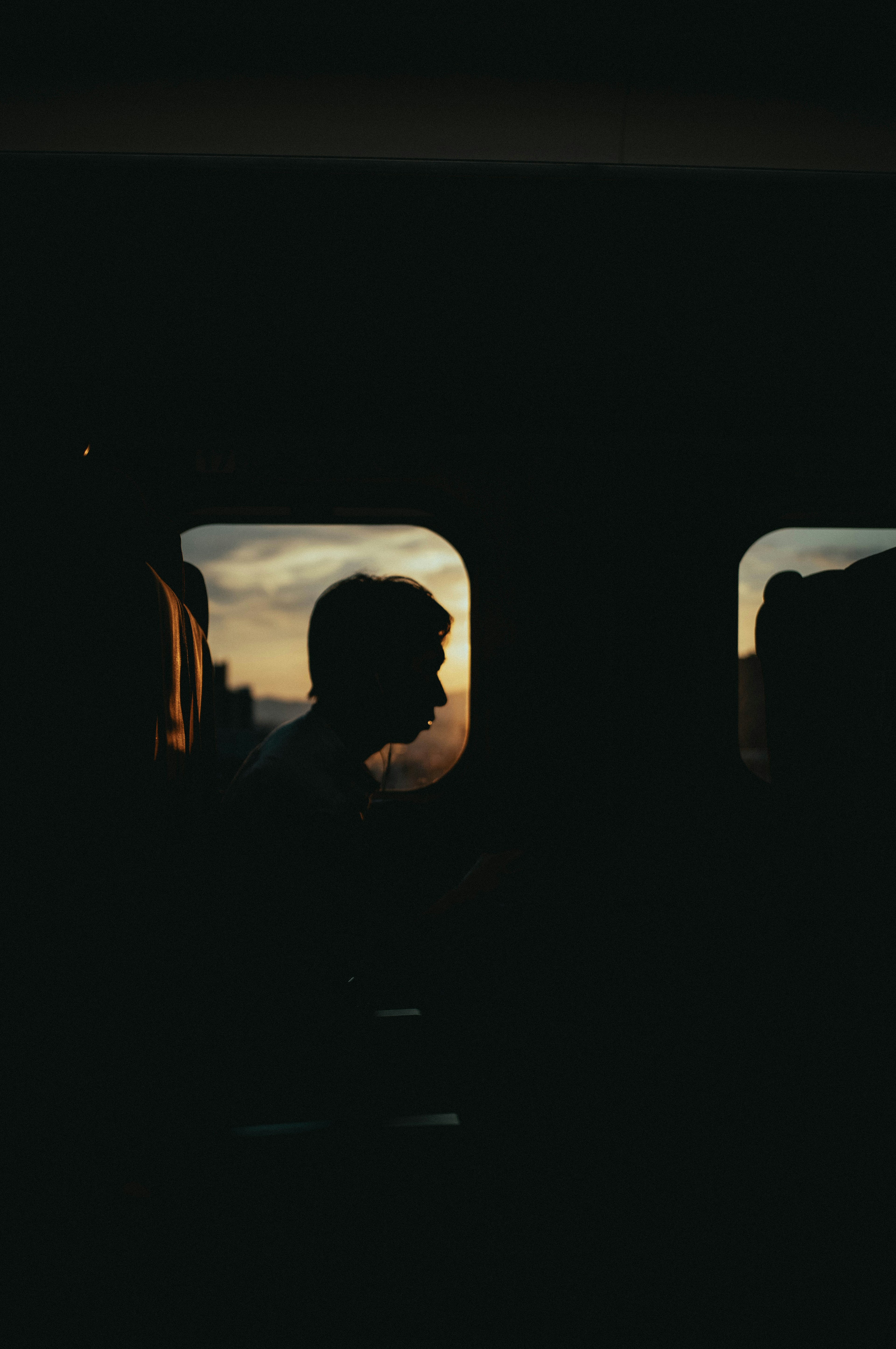 Silhouette d'une personne contre un coucher de soleil vue à travers une fenêtre