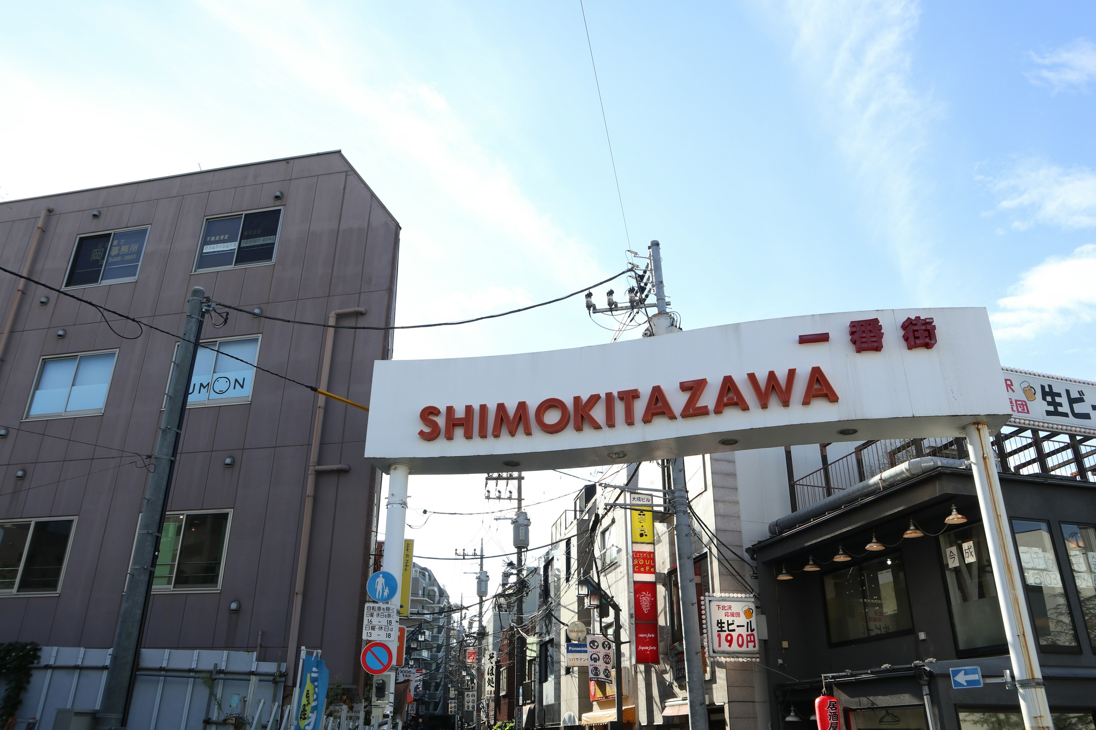 Cartel de entrada de la calle comercial de Shimokitazawa con edificios circundantes