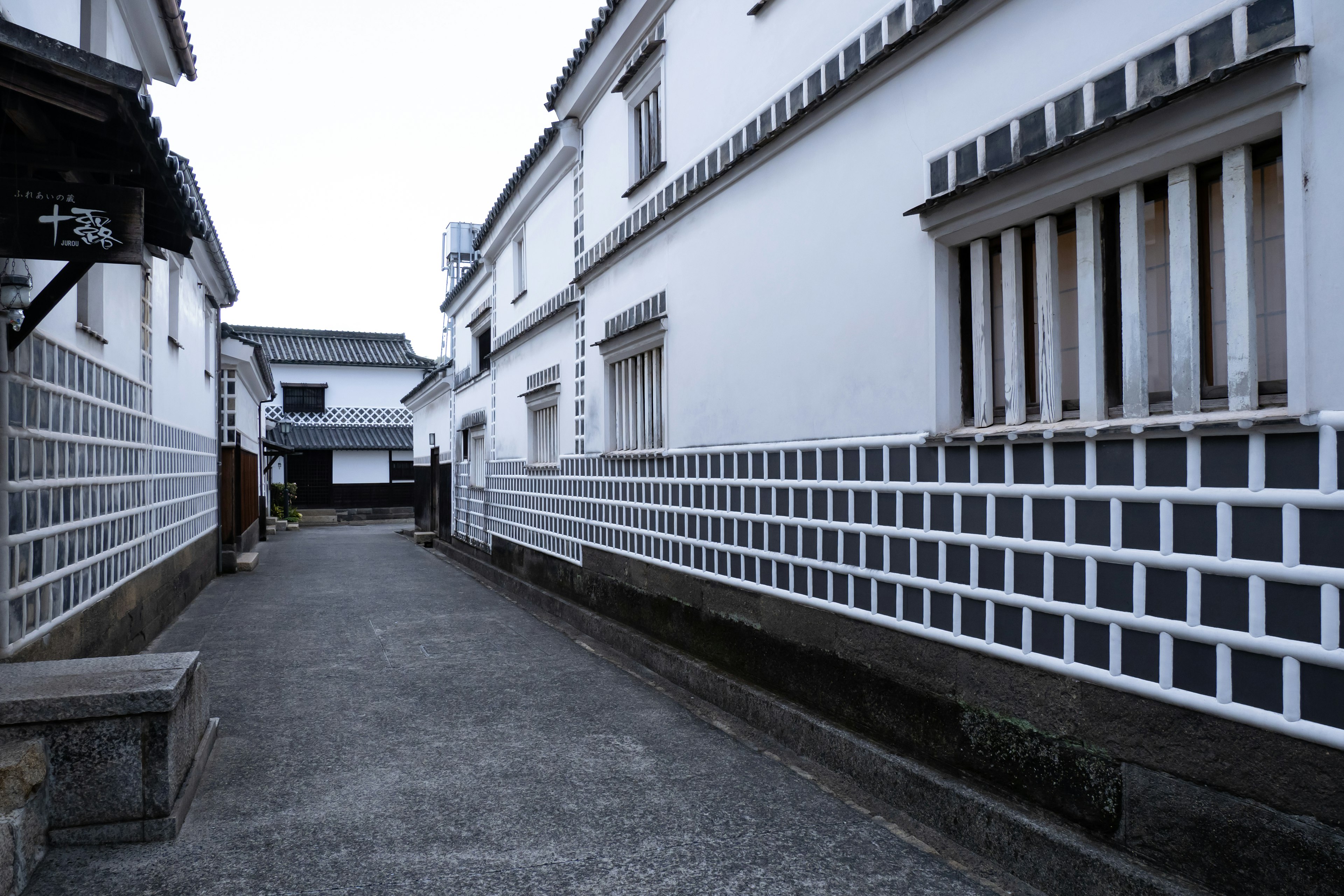 Calle tranquila flanqueada por paredes blancas y casas con patrones de rejilla