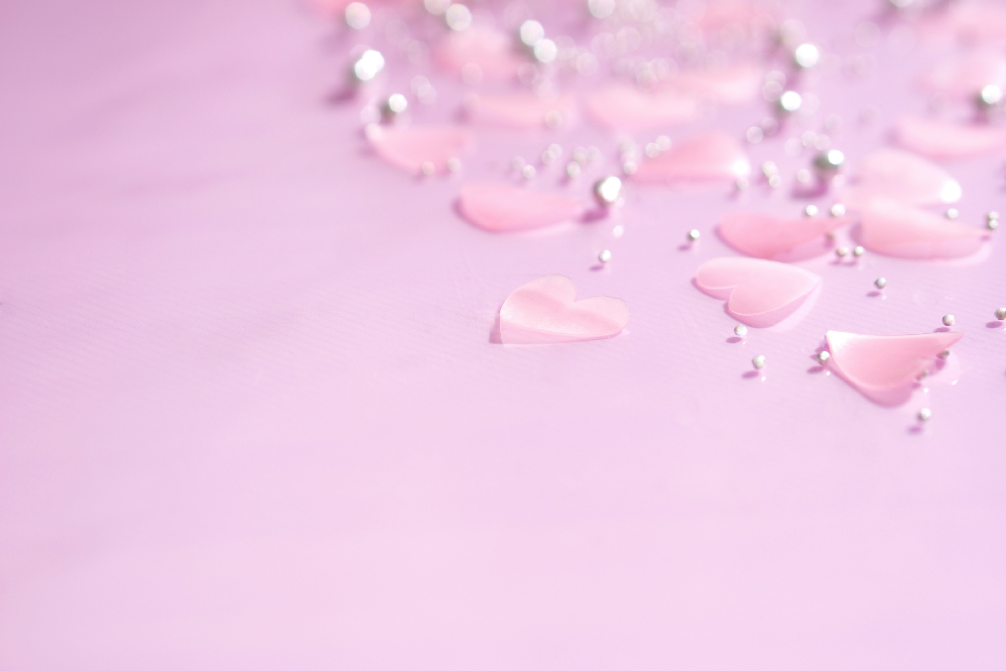 Scattered heart-shaped decorations and beads on a pink background