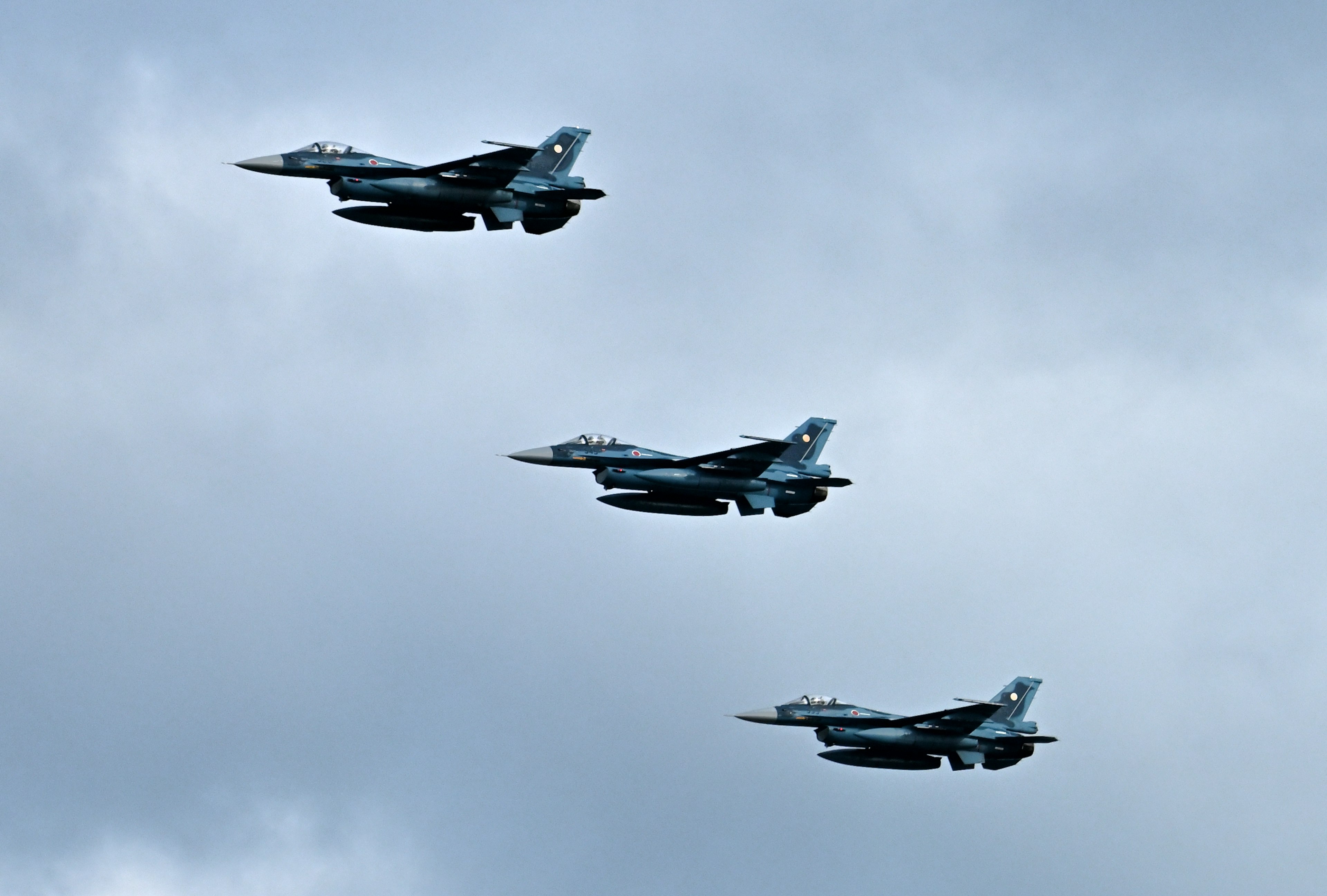 Drei Kampfflugzeuge, die in Formation gegen einen bewölkten Himmel fliegen