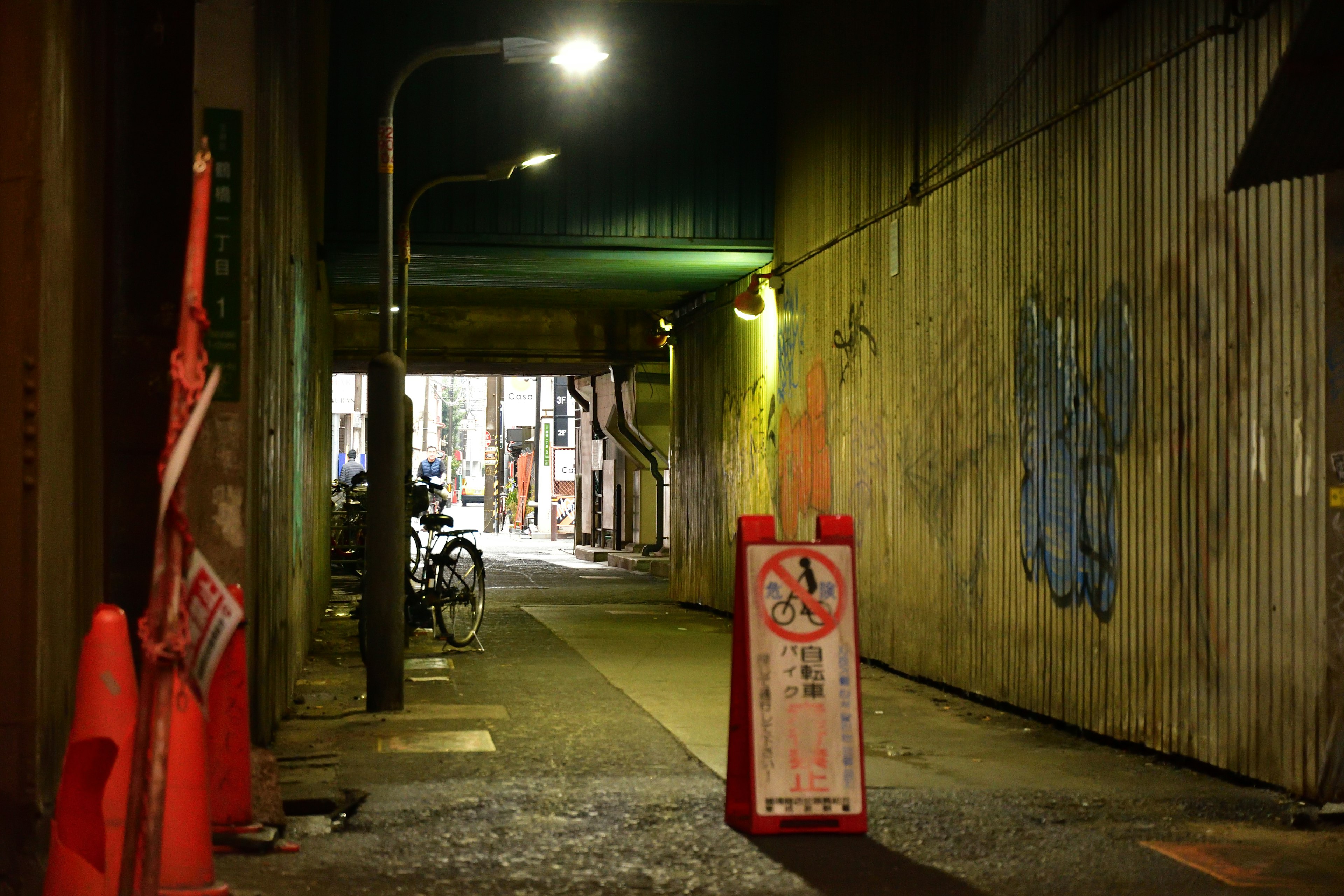 Callejón débilmente iluminado con una bicicleta y un letrero de prohibición