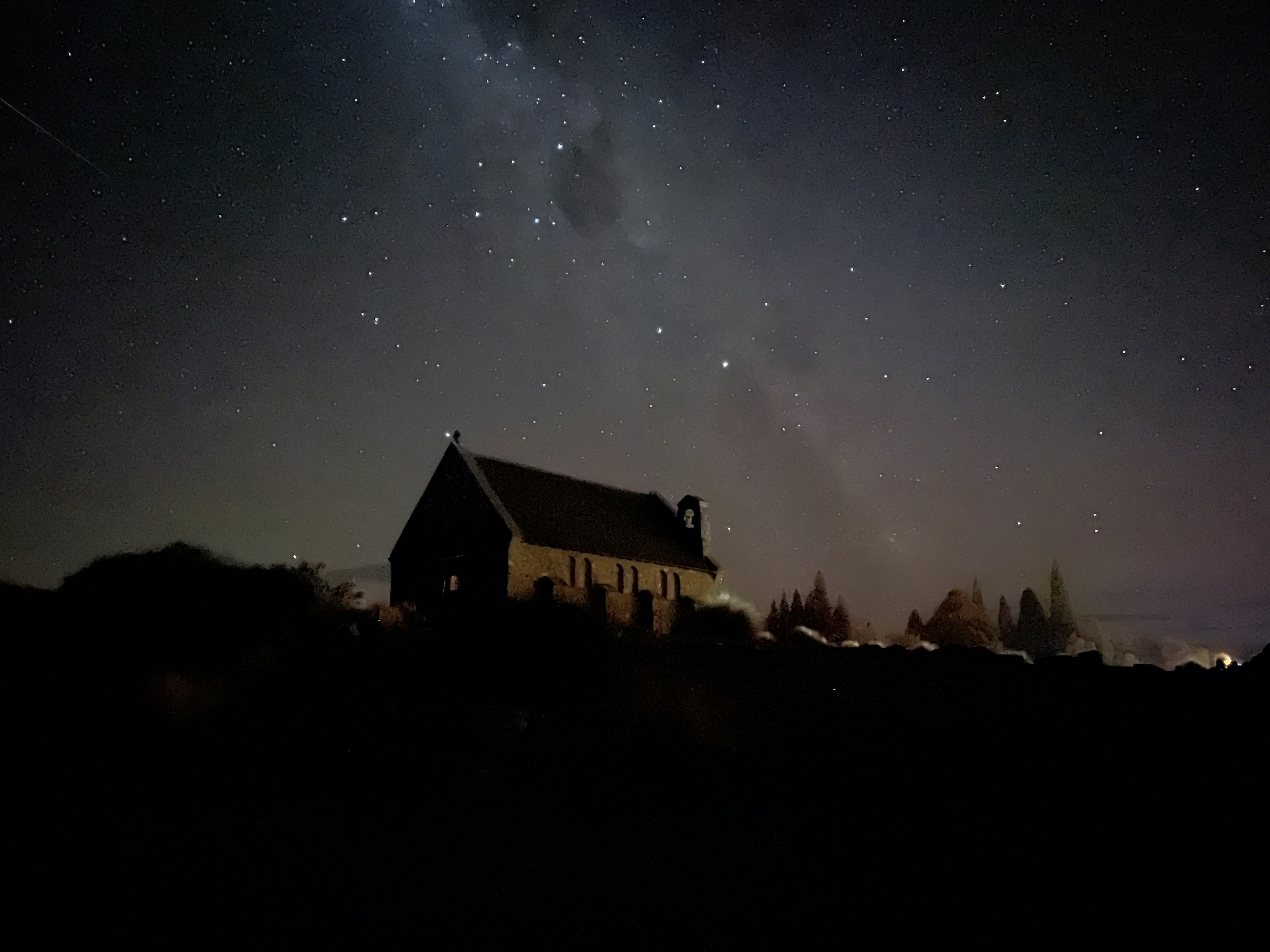 星空の下にある小さな家のシルエットと銀河