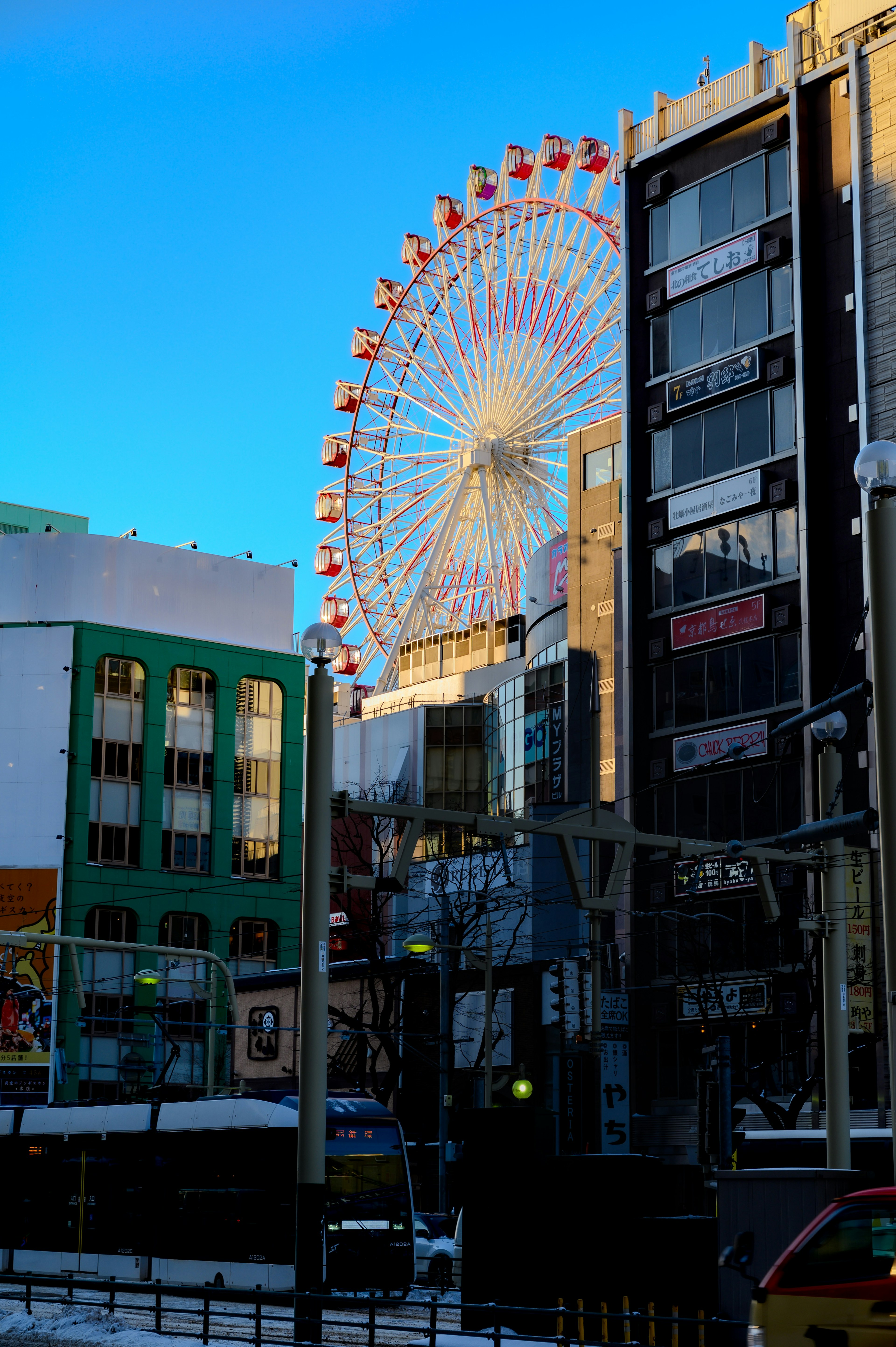 青空の下に見える観覧車とビル群の風景