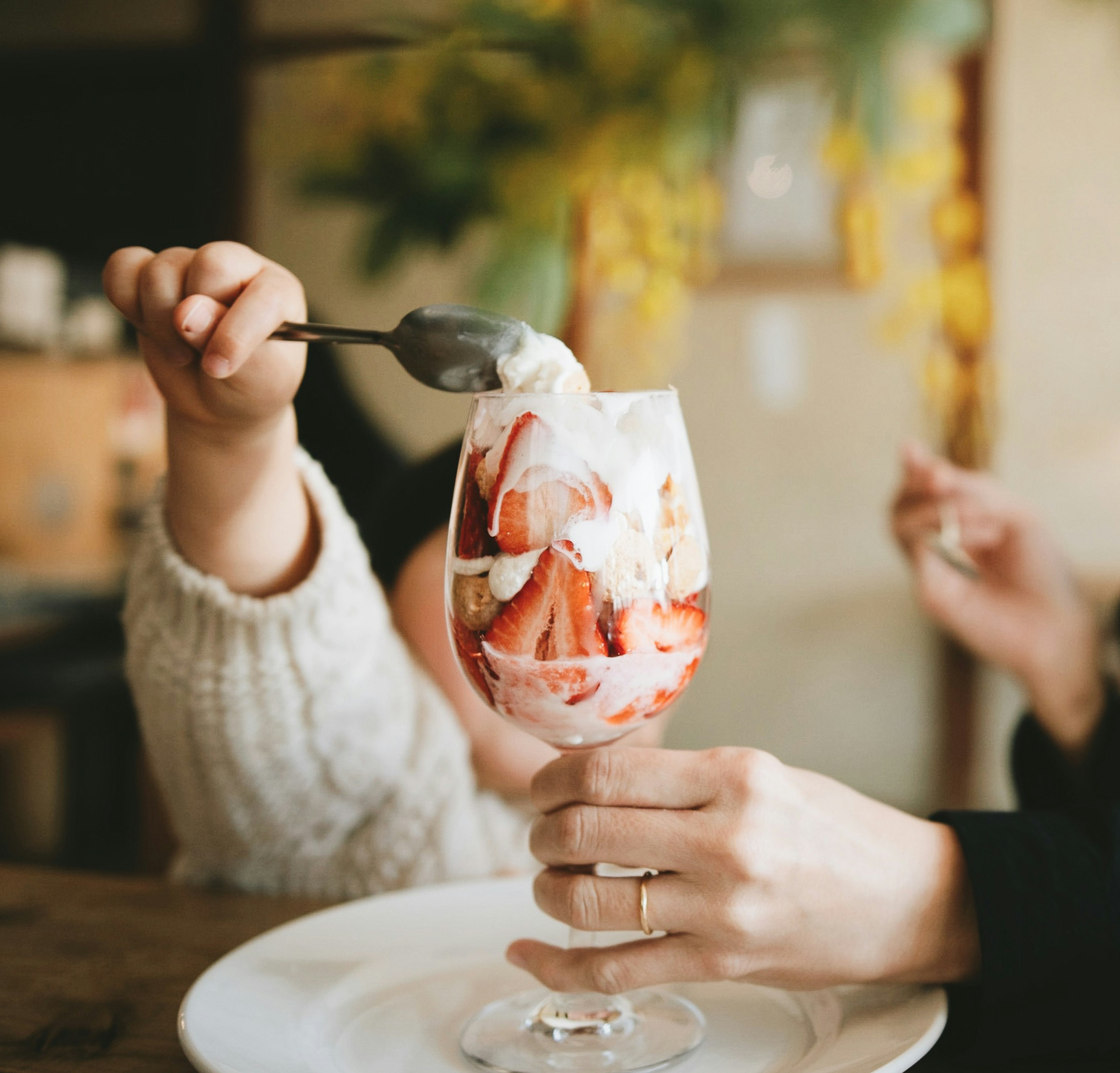 Eine Hand, die ein Erdbeerparfait mit einem Löffel hält