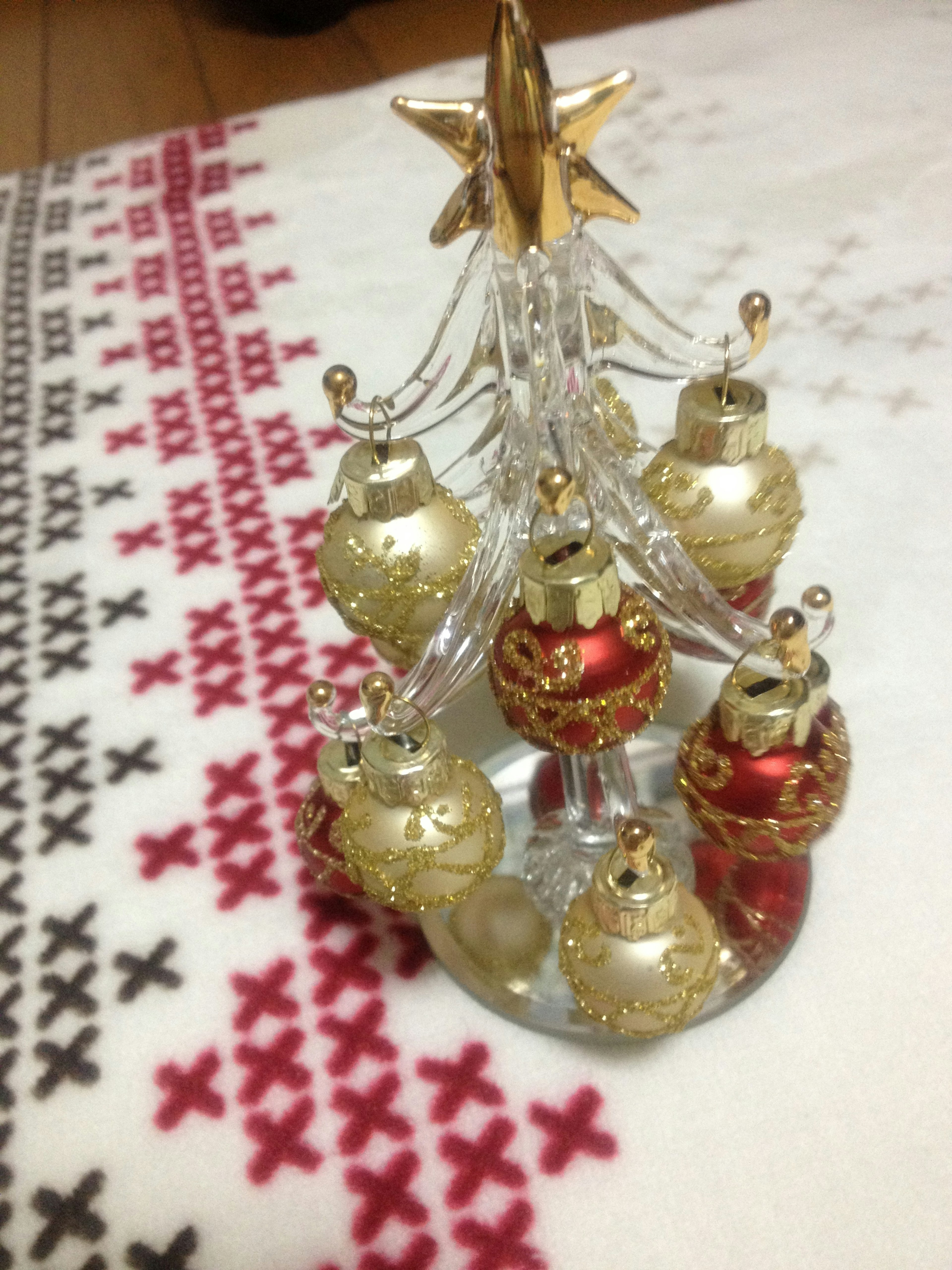 Un pequeño árbol de Navidad adornado con bolas decorativas doradas y rojas