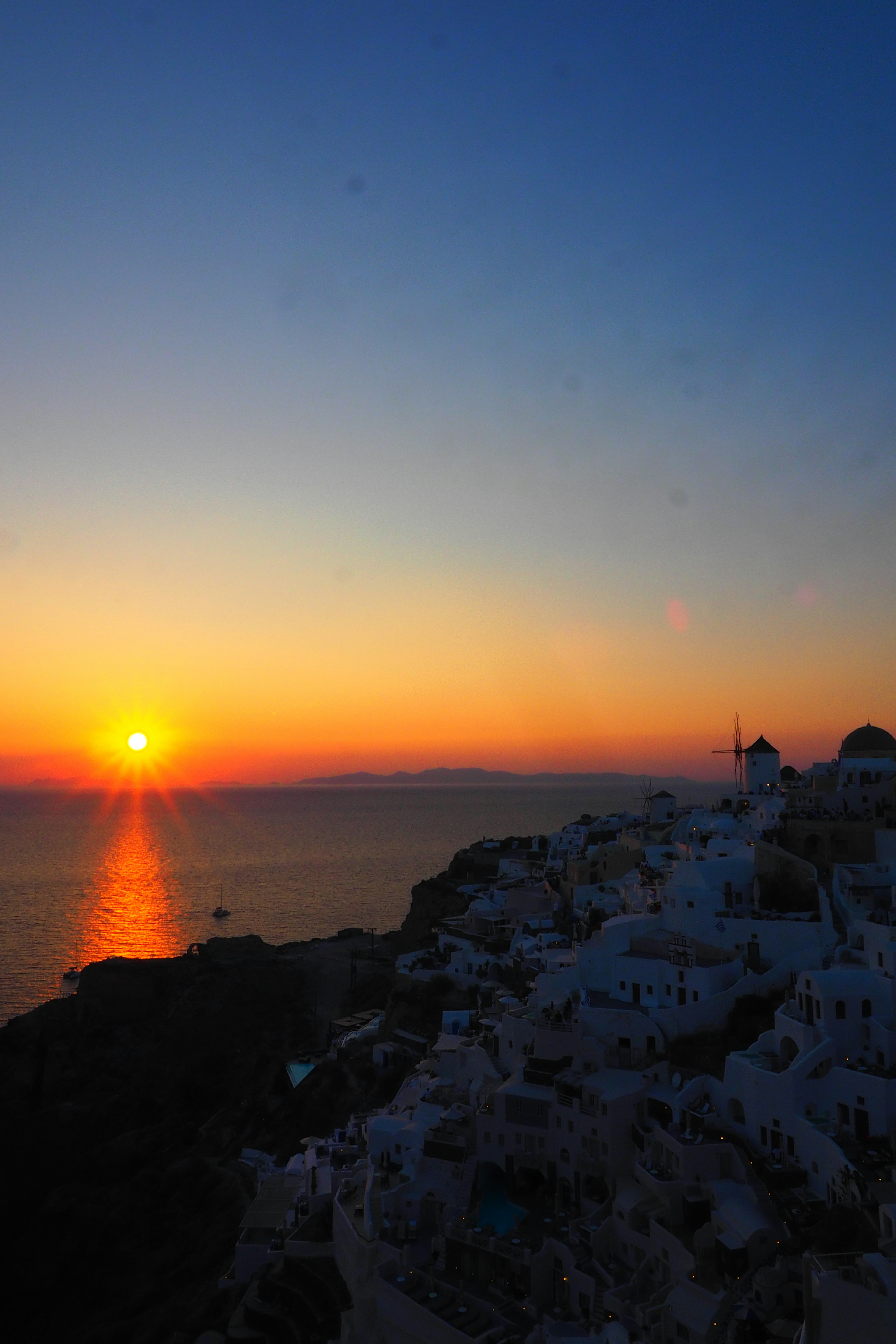 Stupendo tramonto sul mare a Santorini con edifici bianchi sulla collina