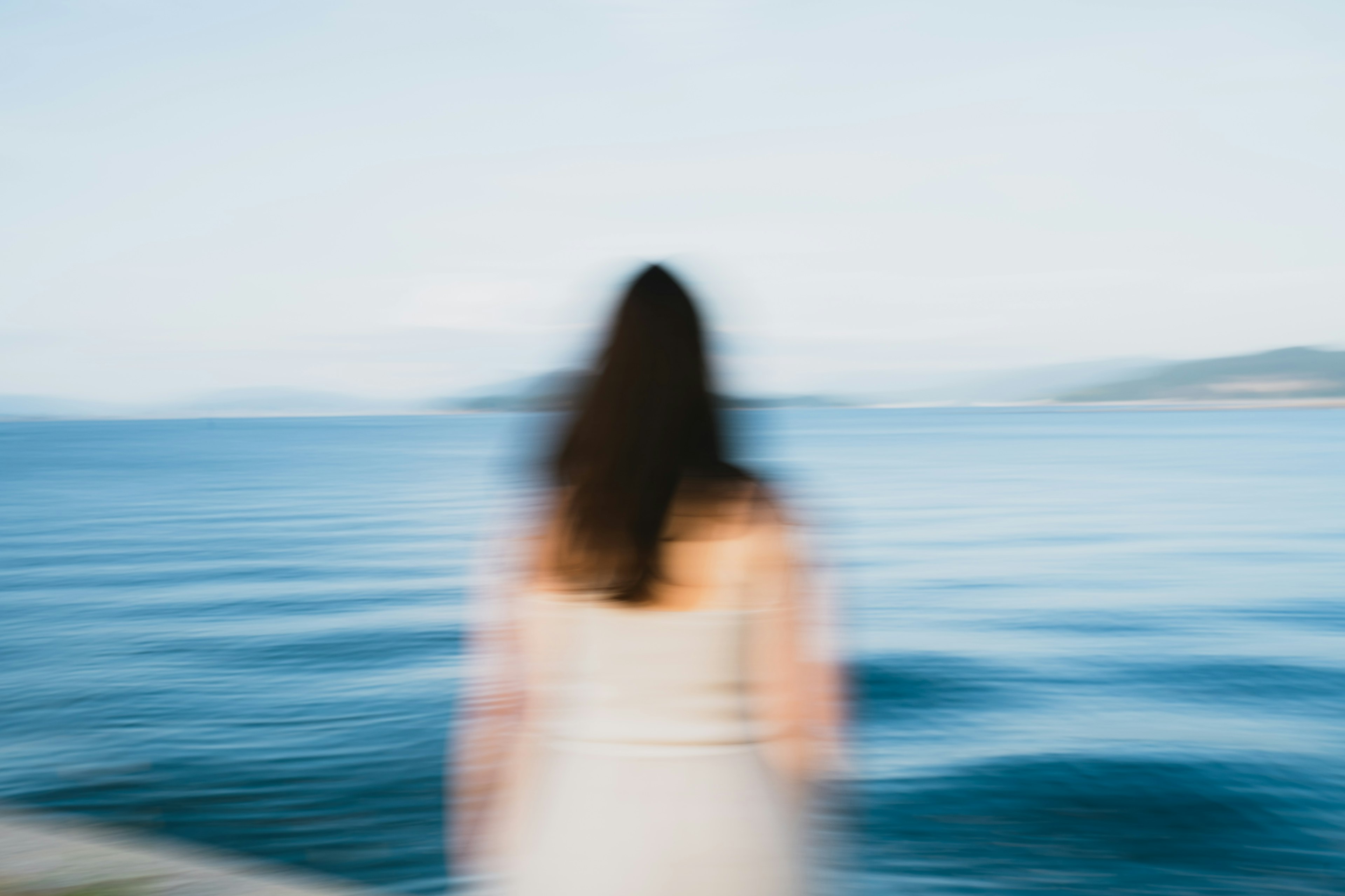 海を見つめる女性のシルエット　ぼやけた背景の青い海と空