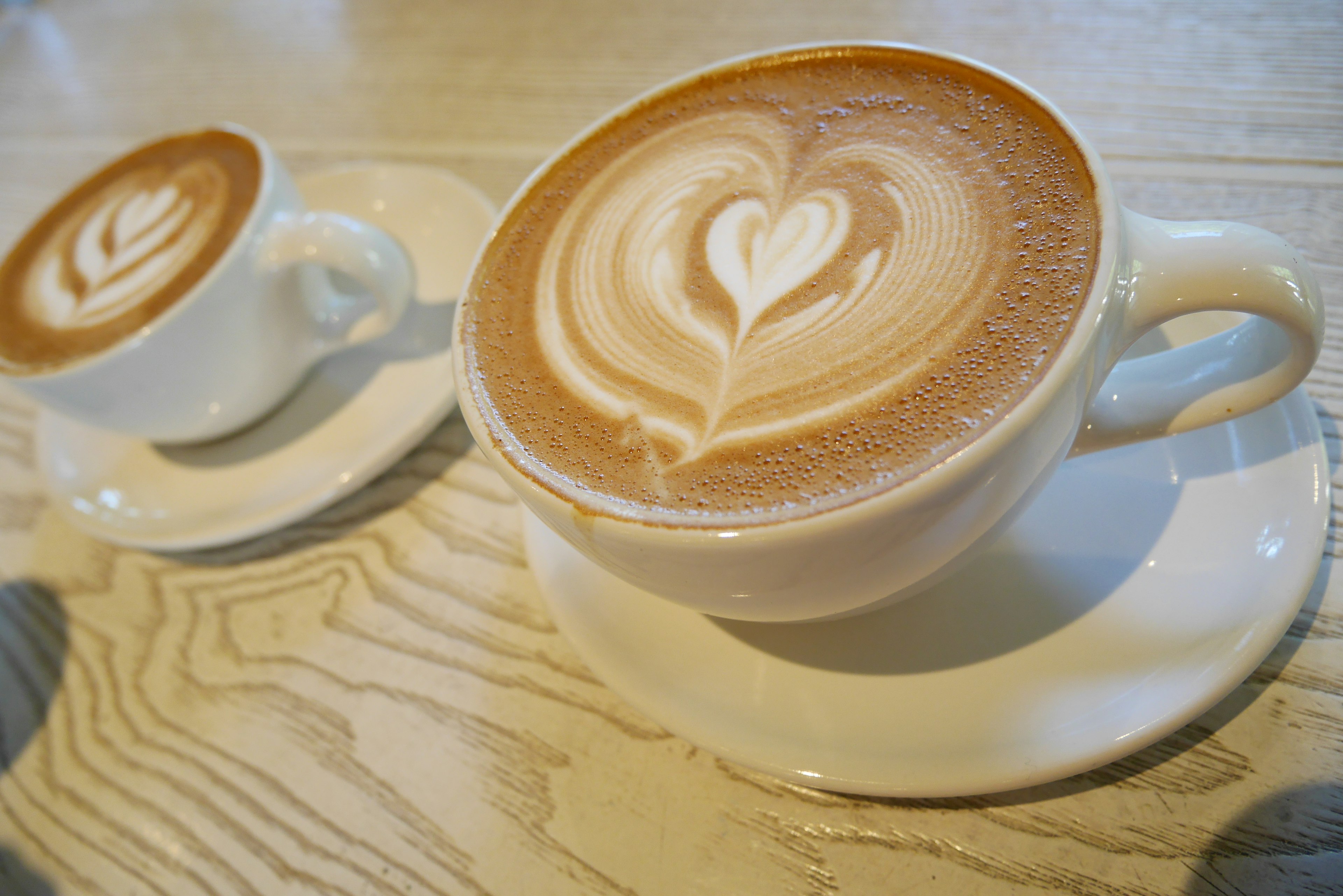 Cappuccino dengan seni latte berbentuk hati dan cangkir kopi kecil