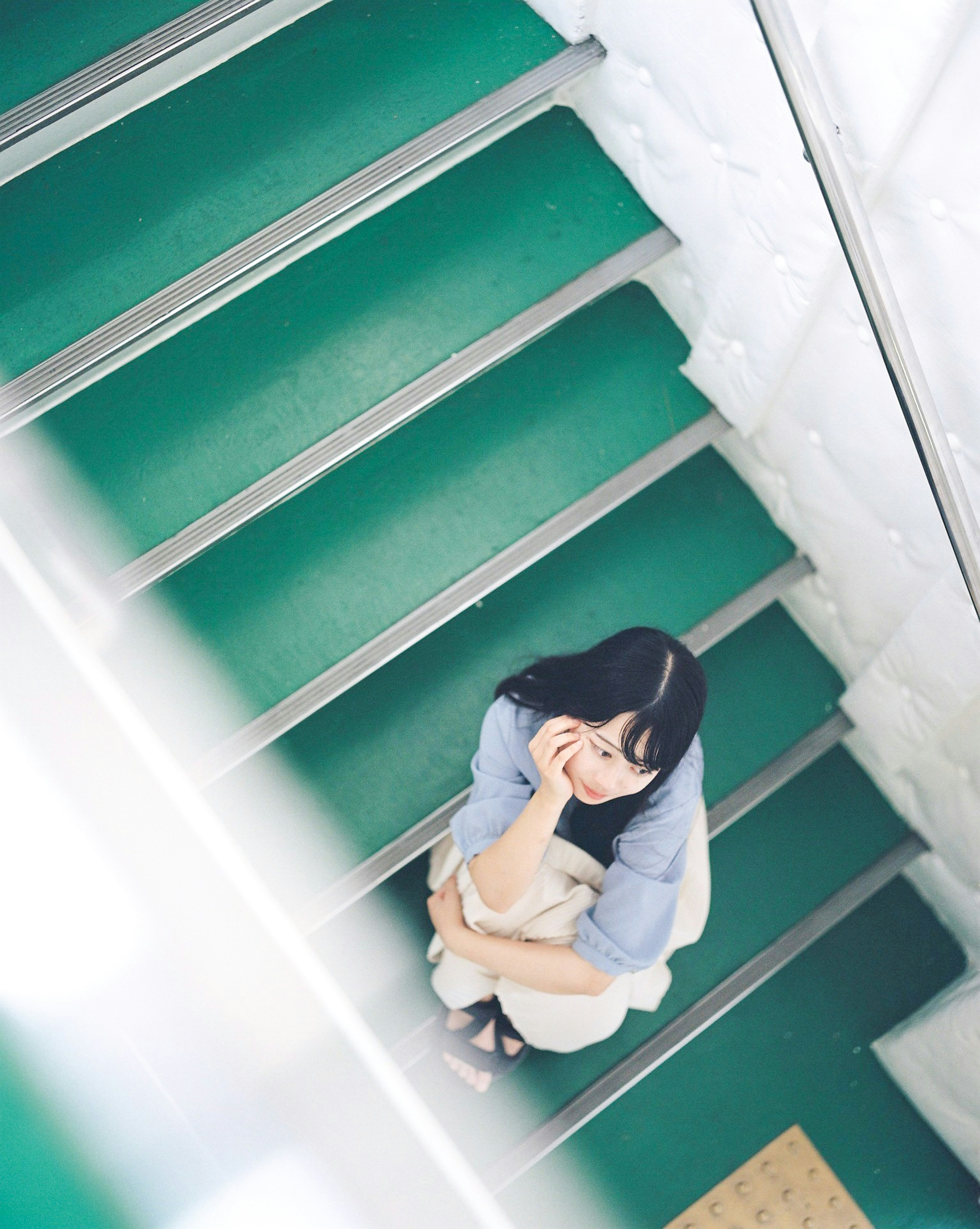 A woman sitting on green stairs from a top-down perspective