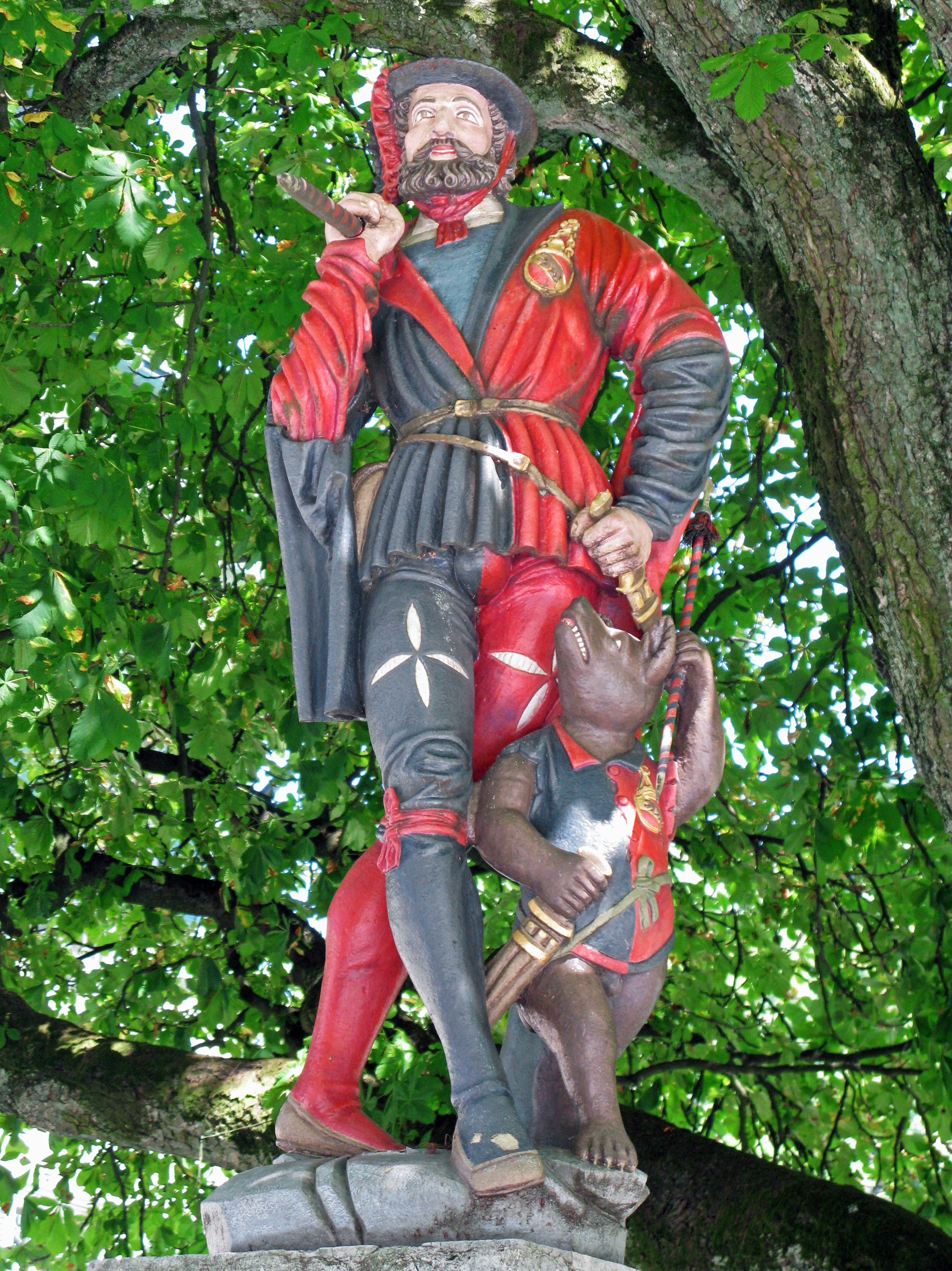 Une statue d'un homme en vêtements rouges se tenant avec un ours