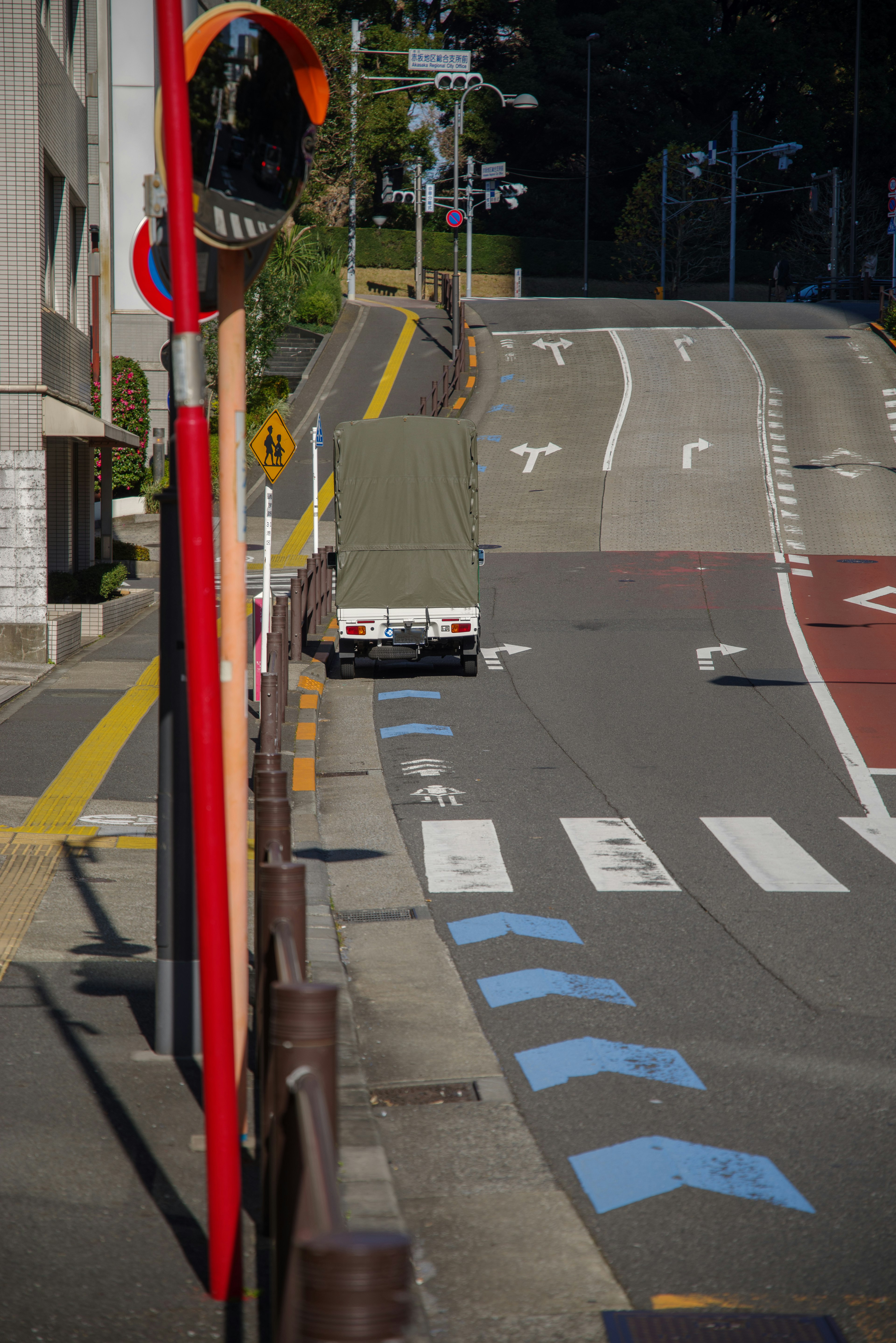 赤い標識と白い線がある道路の写真で、遠くにトラックが走っている