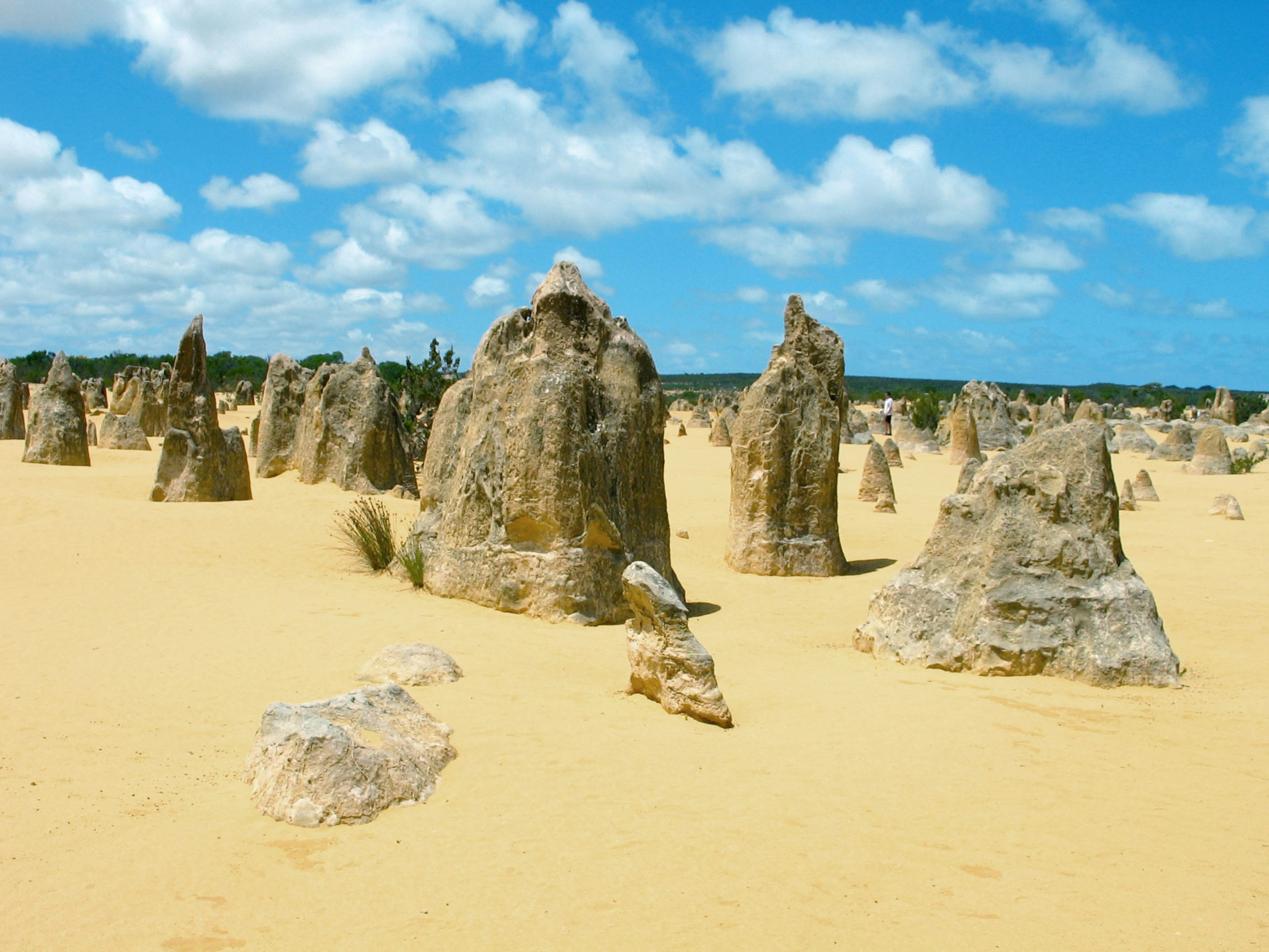 Unique rock formations in a sandy desert under a blue sky