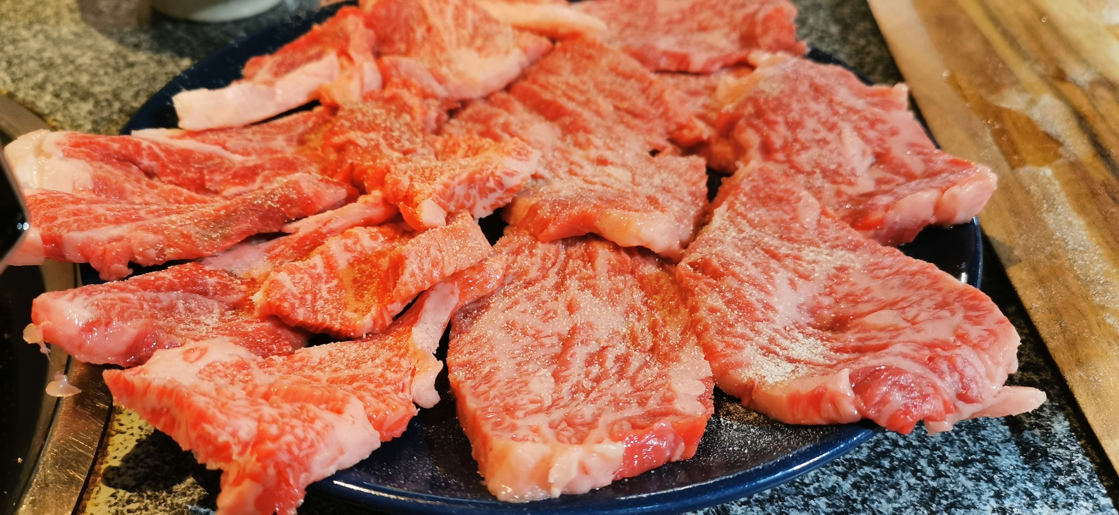 Fresh slices of meat arranged on a black plate