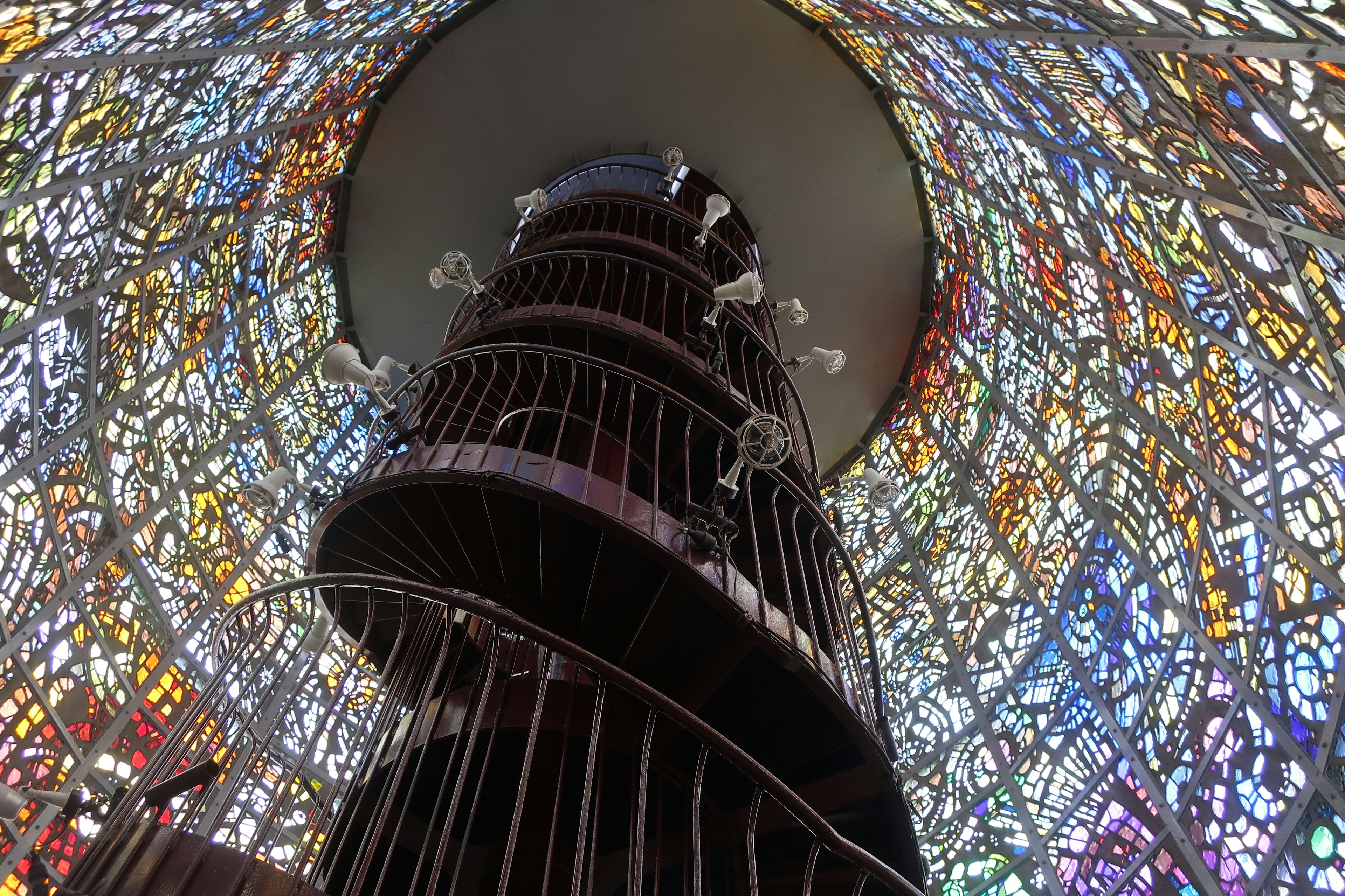 Interior of a spiral staircase surrounded by colorful stained glass