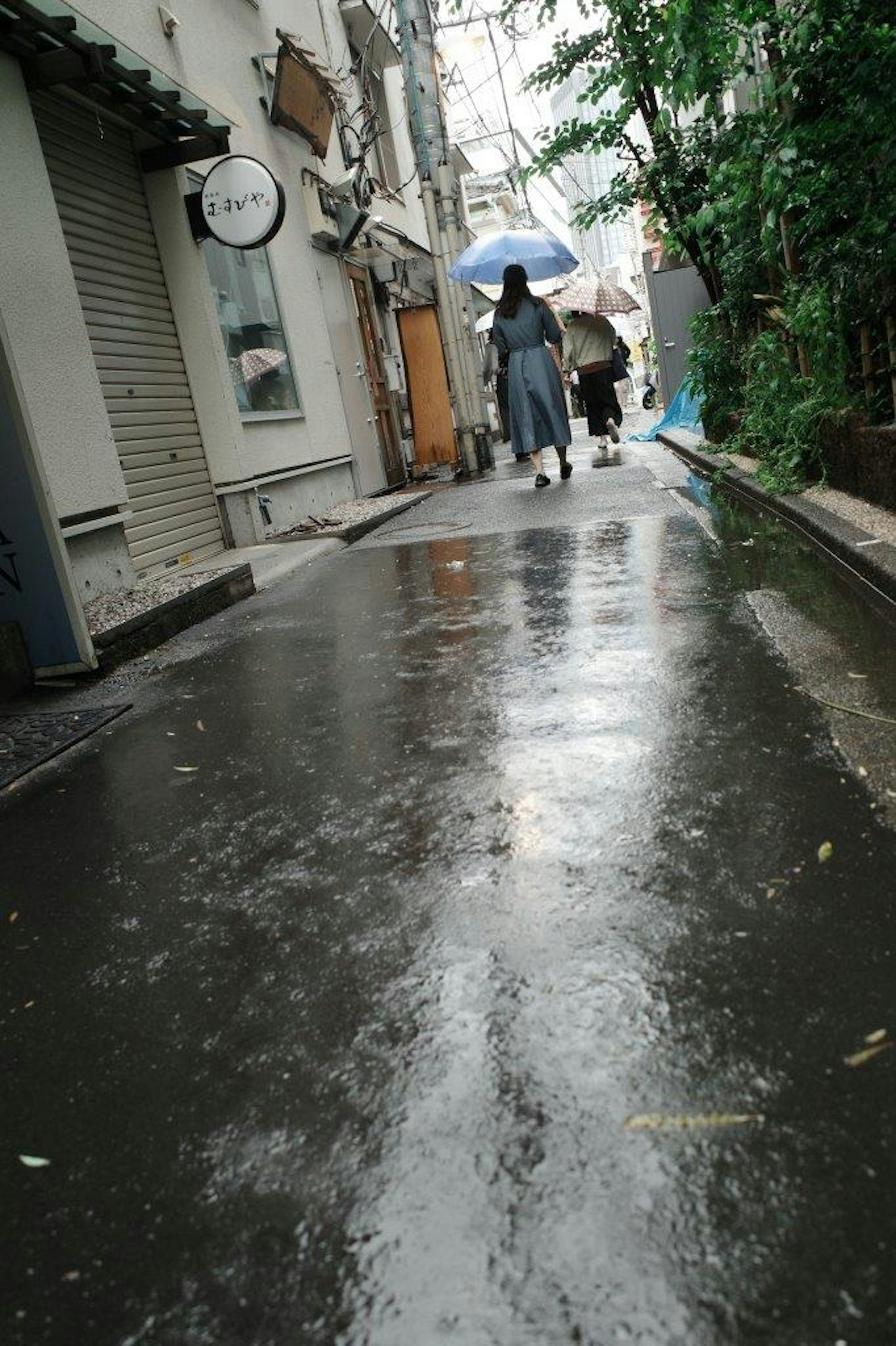 雨の中の狭い路地にいる傘を差した人々