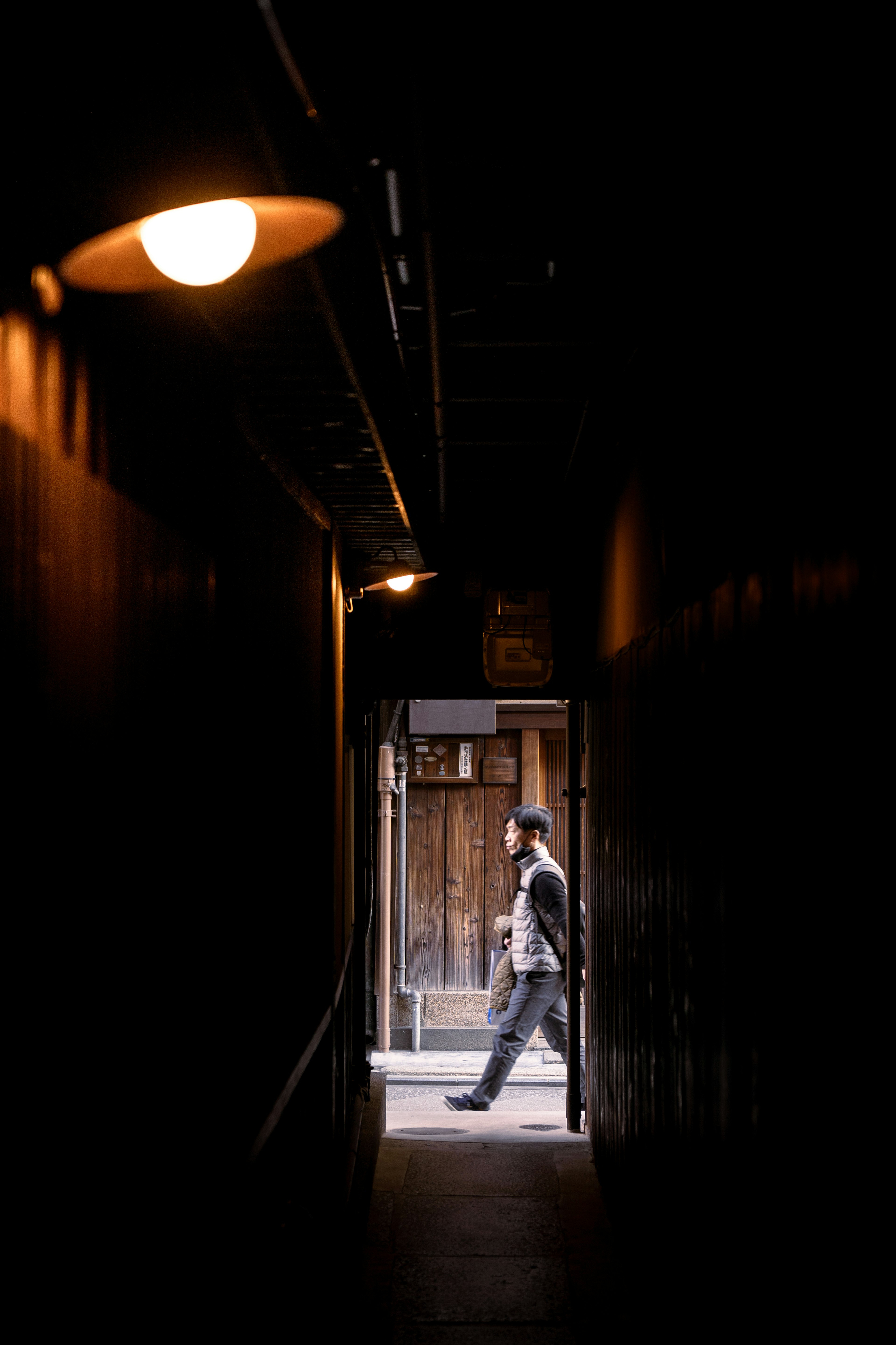 A person walking through a dark corridor towards an illuminated exit