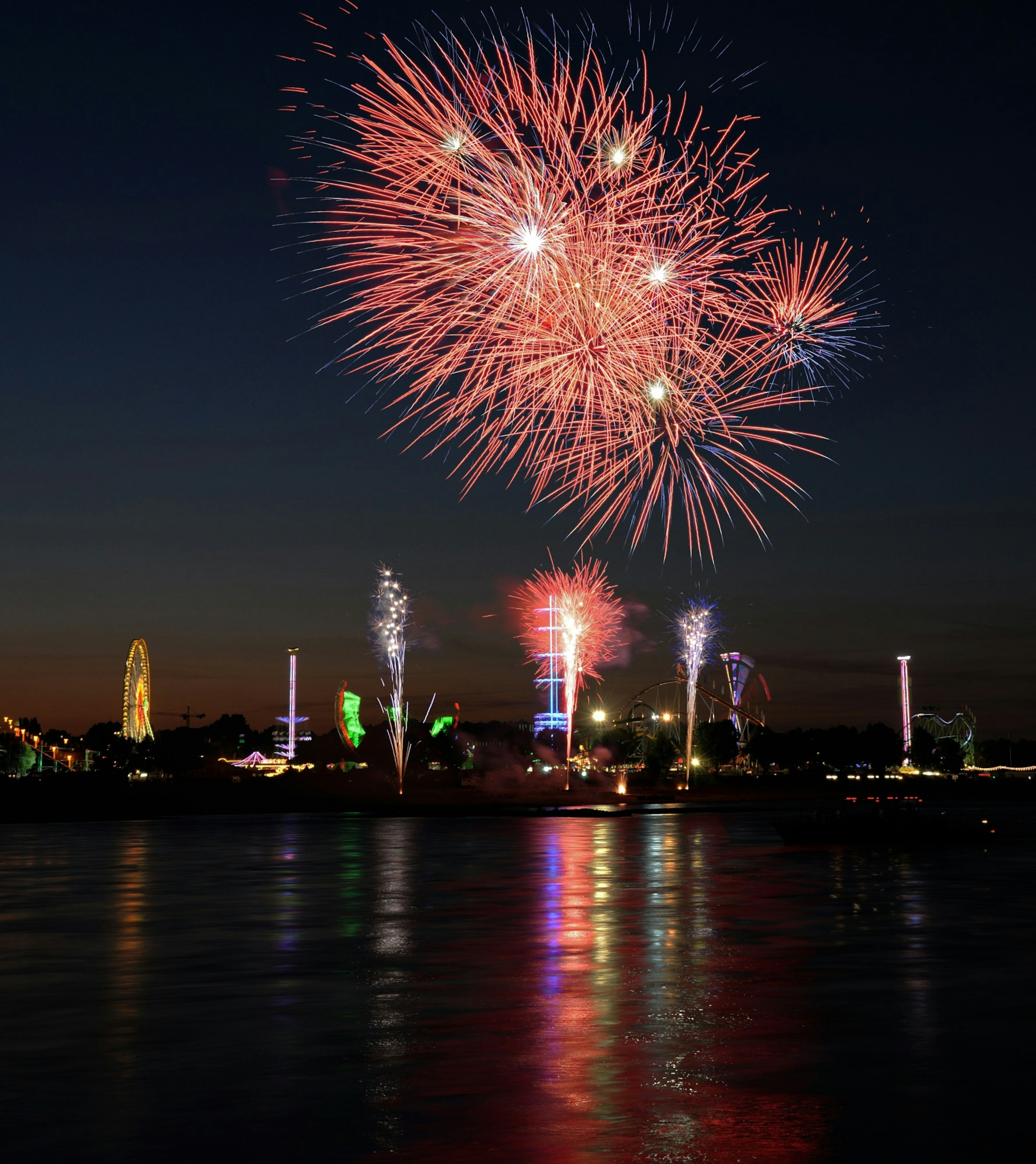 Des feux d'artifice colorés illuminant le ciel nocturne reflété sur l'eau