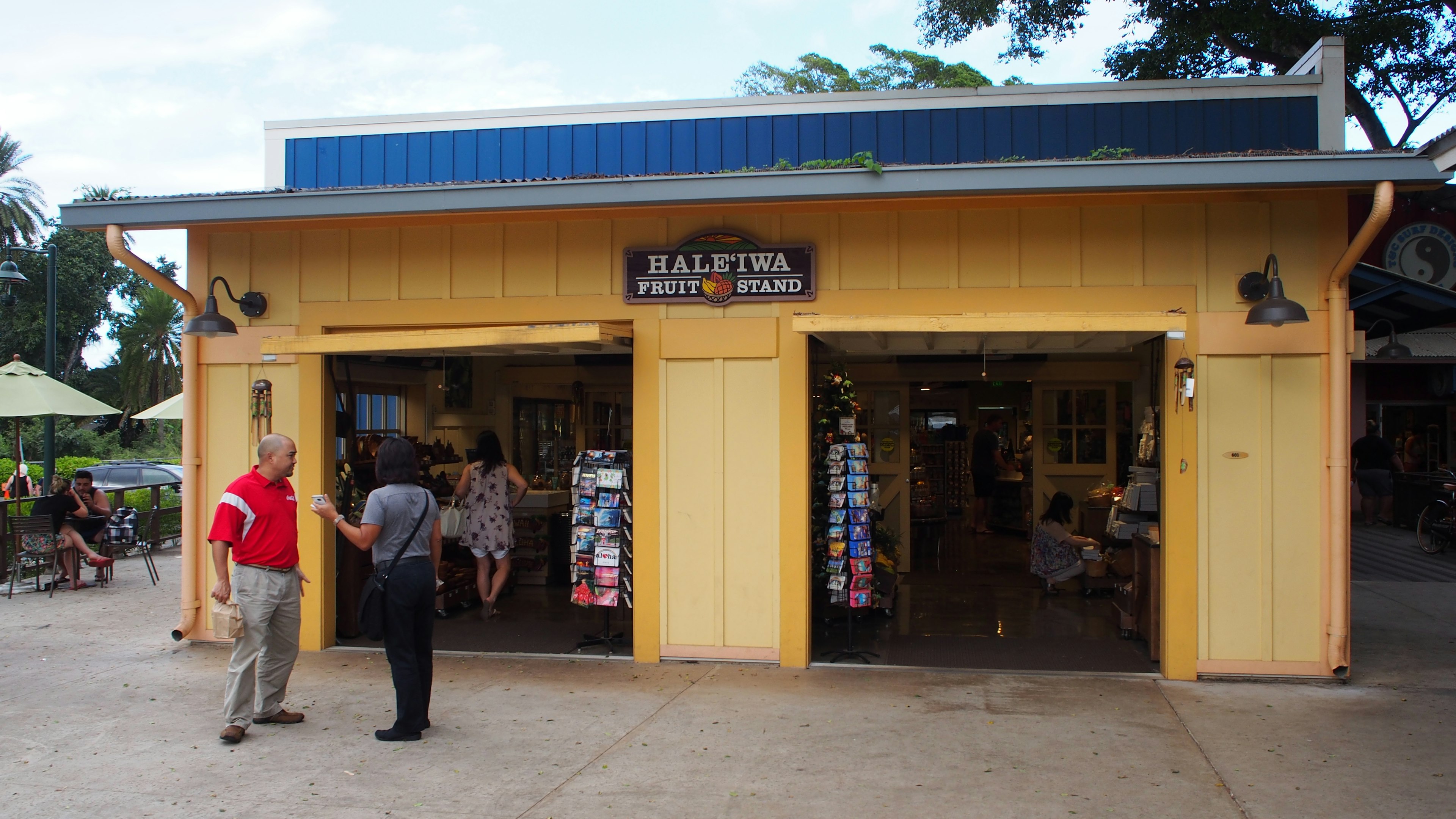 A storefront with yellow walls featuring two people outside